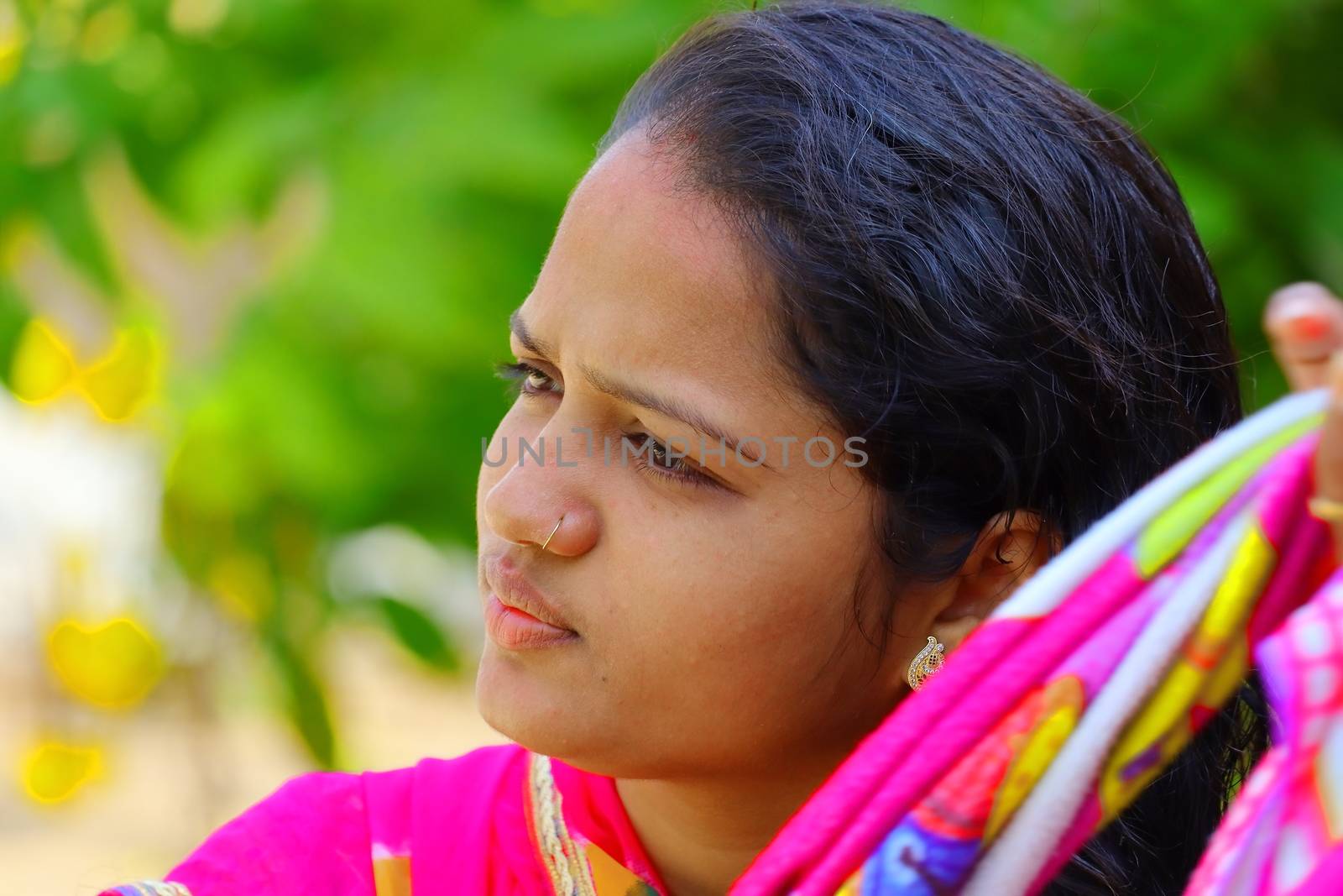 a portrait head shot of young Indian girl with blur green nature background