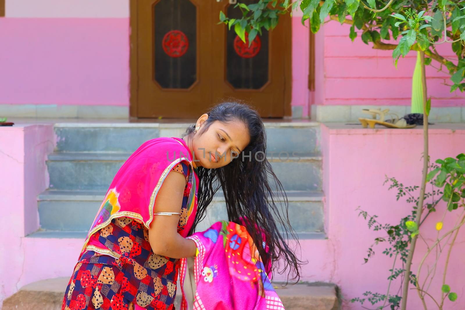 A young girl drying black hair with a towel nearby home, concepts for hair care