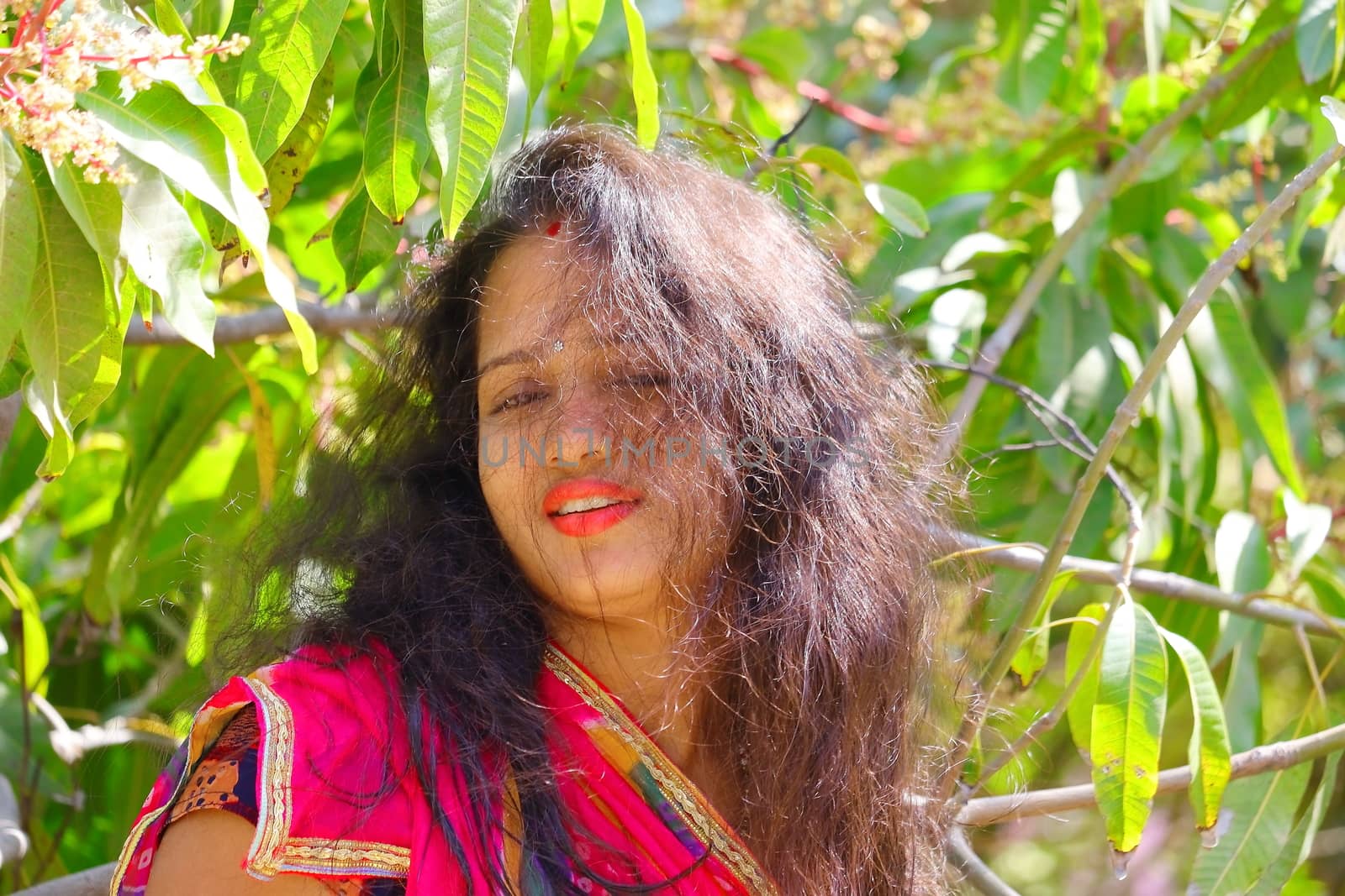 Portrait head shot of a indian young beautiful girl in open bright black hairs and polished red lips , concepts for women health care