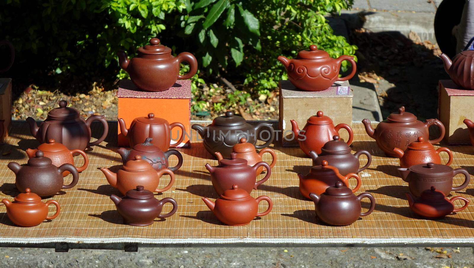 An outdoor vendor sells teapots made from characteristic red clay

