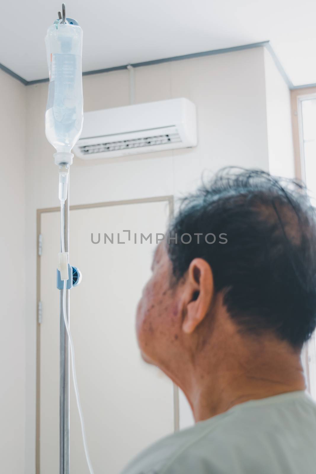 Patient asian elder man 70s with saline intravenous at C-line or A-line on a elderly patient hand on patient bed in intensive care unit (ICU.) room at hospital.