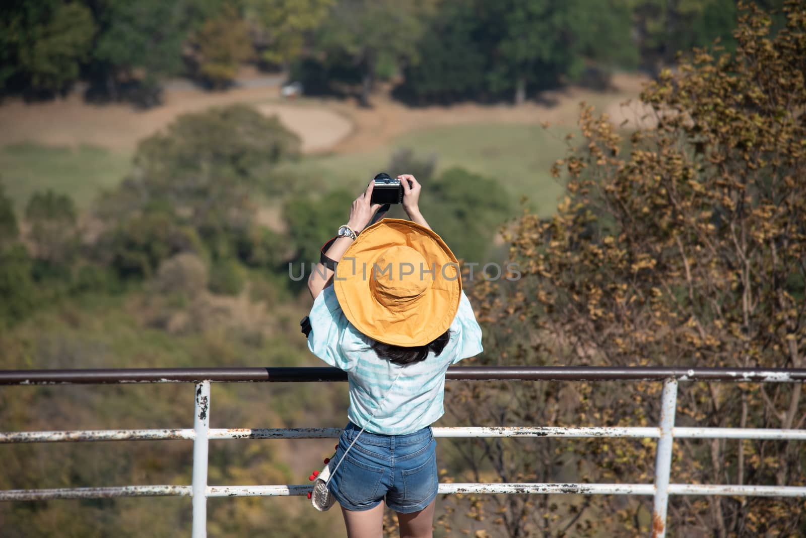 Asian pretty cute woman with hat relax and use smartphone at seaside city landscape viewpoint on mountain with happy and freedom emotion in concept travel, vacation, leisure in life