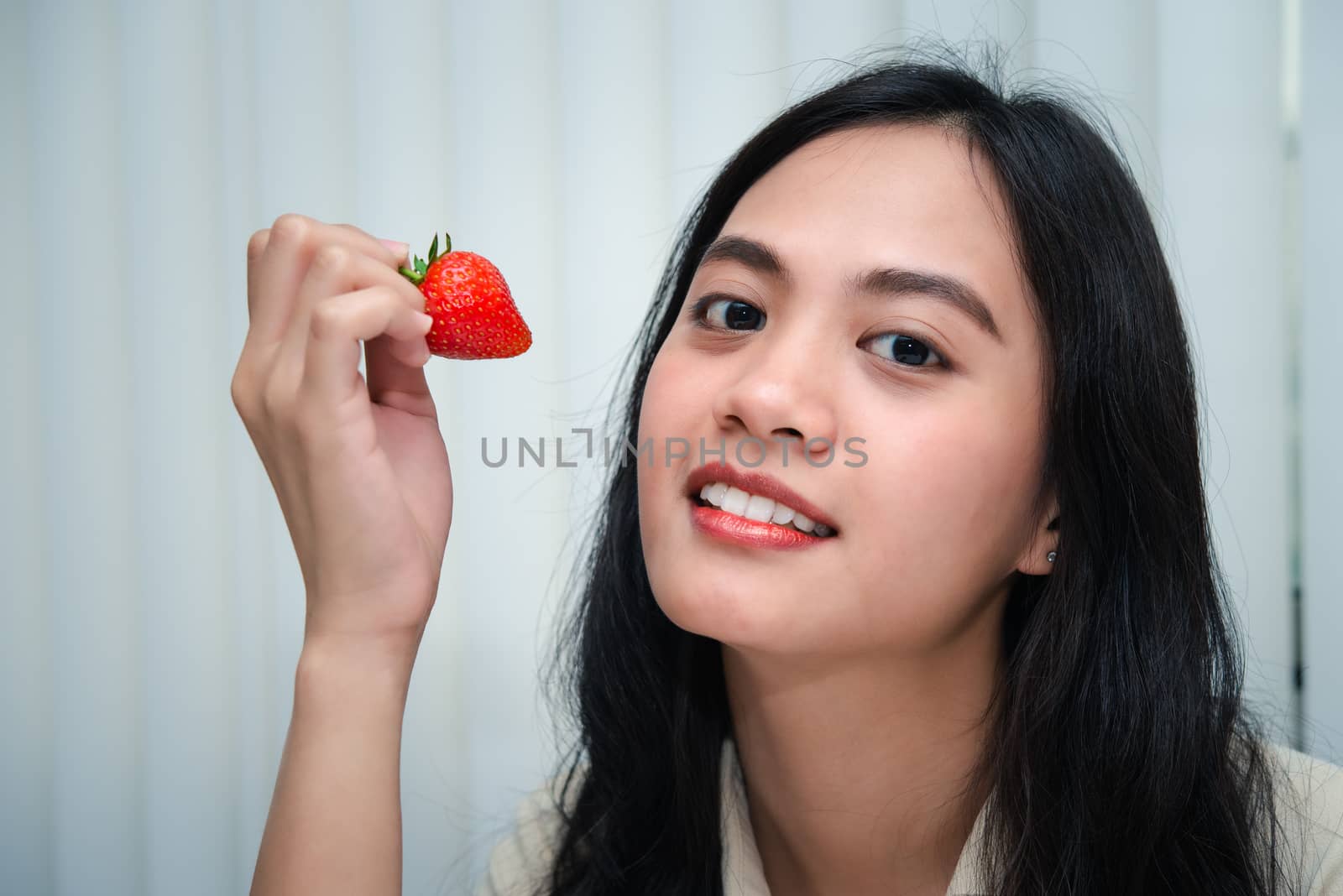 Asian pretty woman holding and eating fresh strawberry is red berry fruit color and sweet juicy with enjoy and happy emotion in concept food, healthy eating in life