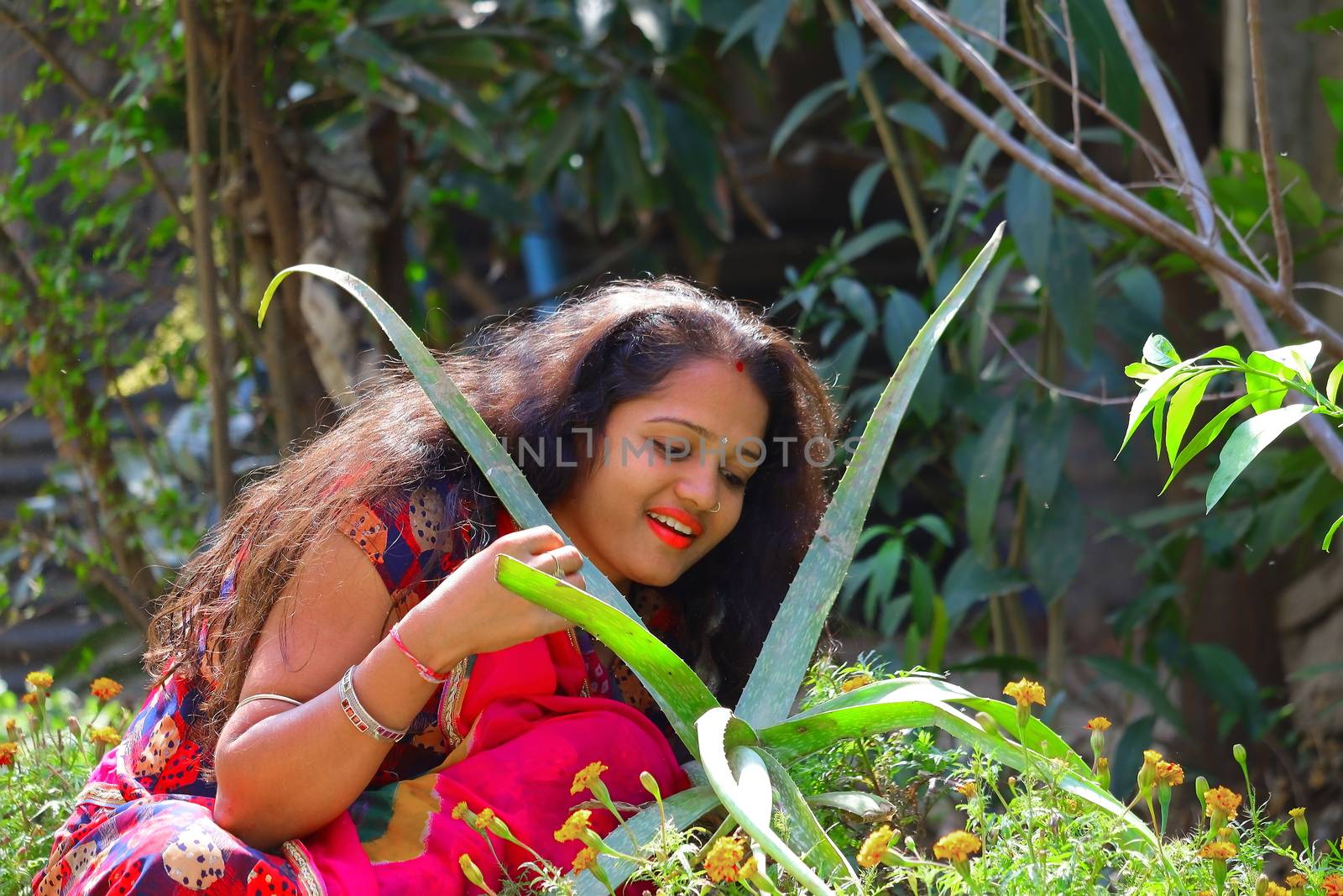 A beautiful young girl's fair face with polished red lips and a close-up image of aloe vera green leaves, concepts for skin care and women health