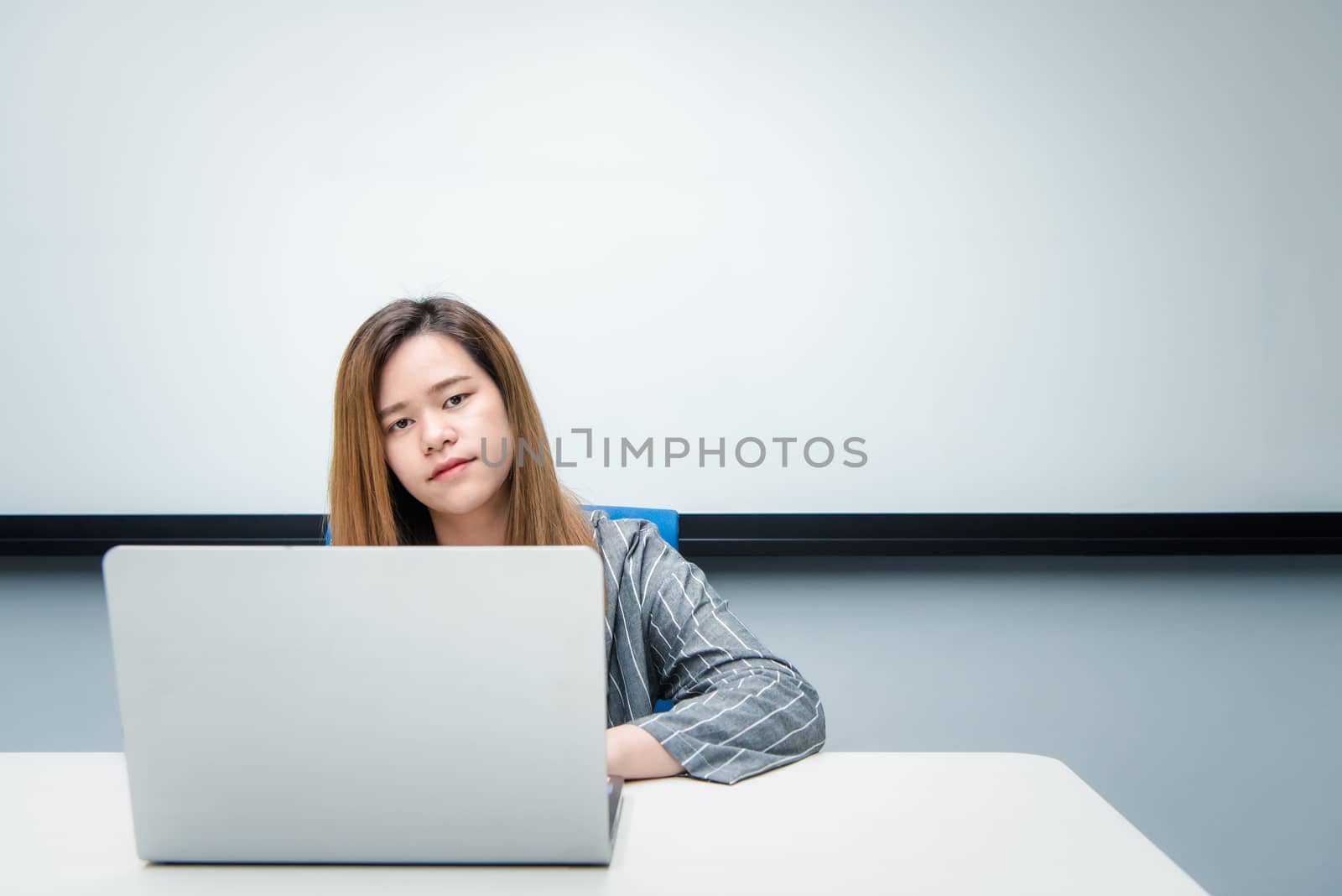 Asian woman is student, businesswoman working by computer notebook, laptop in office meeting room with whiteboard in background with happy and relax emotion in concept working woman, success in life