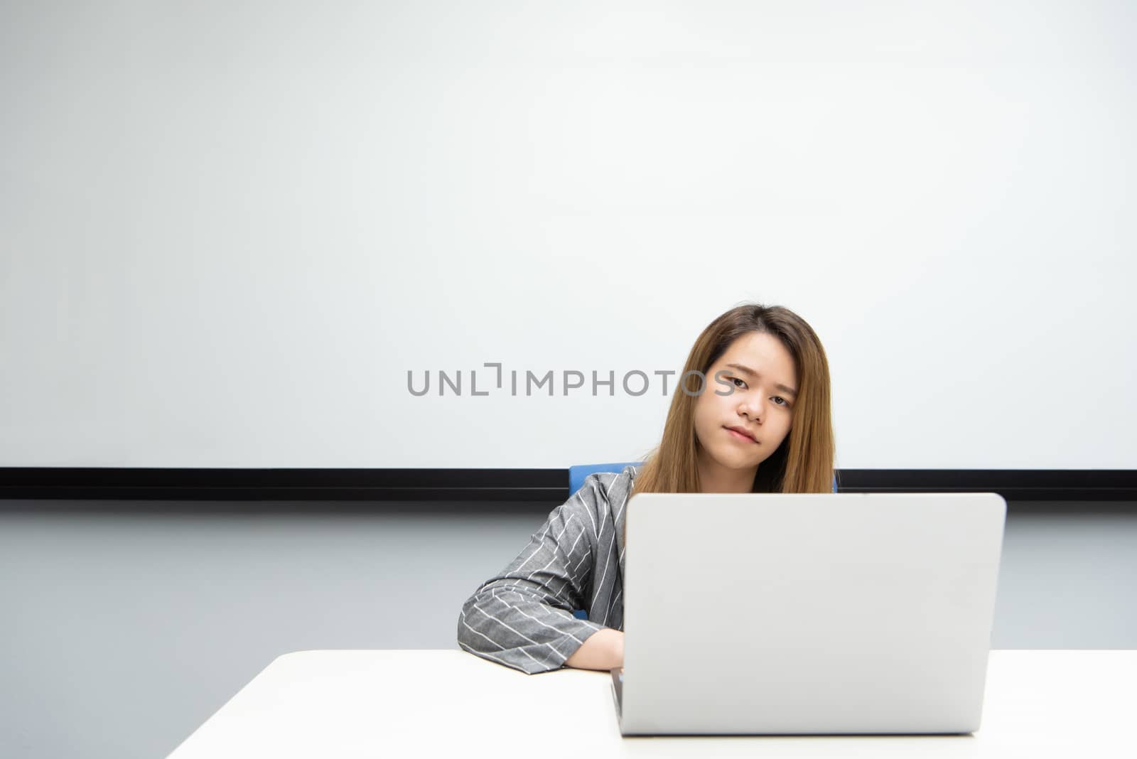 Asian woman is student, businesswoman working by computer notebook, laptop in office meeting room with whiteboard in background with happy and relax emotion in concept working woman, success in life