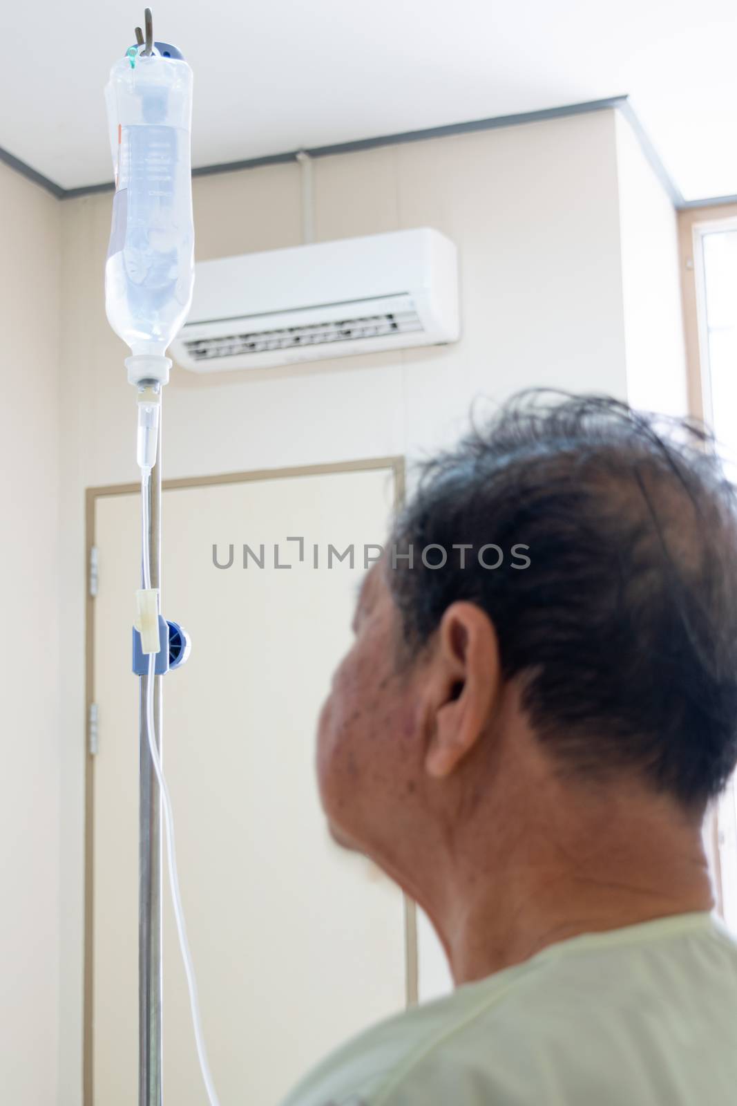 Patient asian elder man 70s with saline intravenous at C-line or A-line on a elderly patient hand on patient bed in intensive care unit (ICU.) room at hospital.