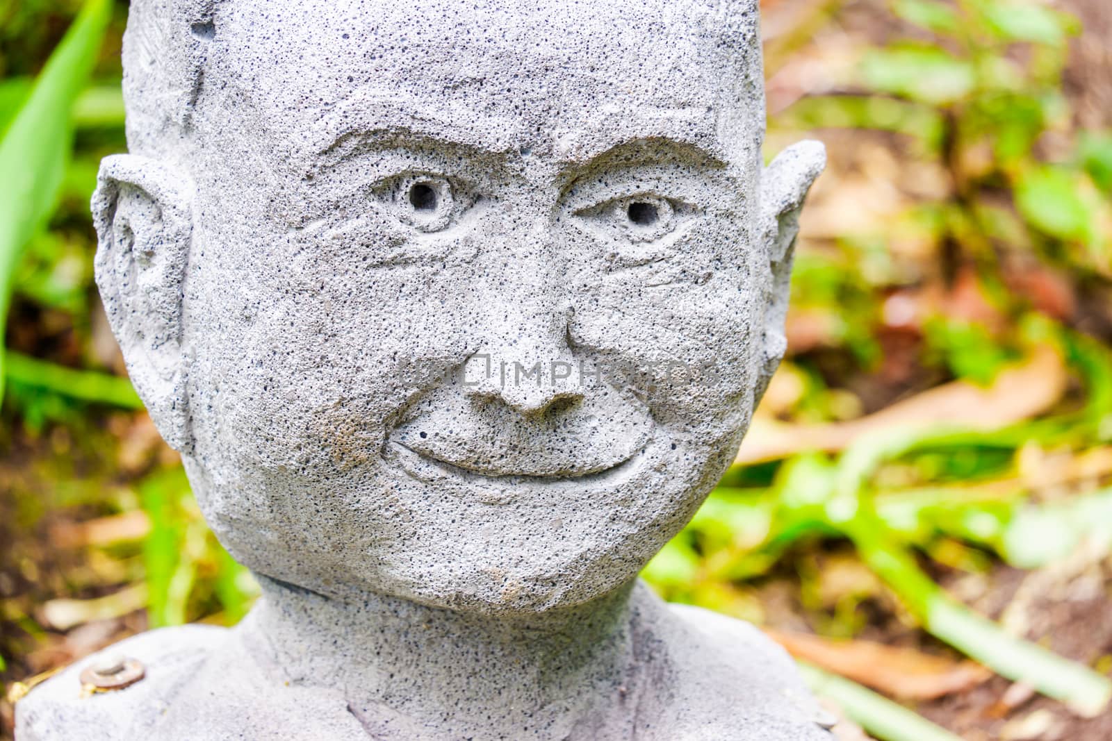 Details of the cute stone doll face that adorned the garden. Good looking monk stone face with sunshine on.