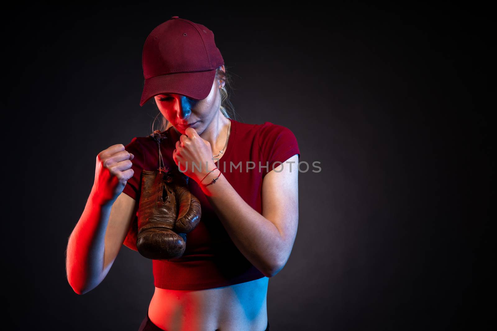 portrait of woman with old boxing gloves on black background, copy space.
