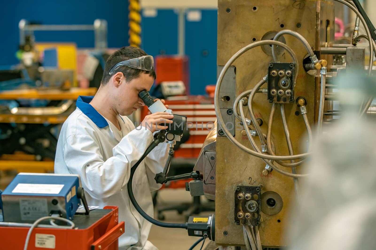 the engineer checks the correct setting of the metal mold for castings in the factory using a microscope.