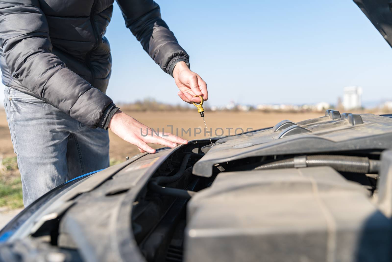 the driver checks the oil level in the car at fault on dirt road by Edophoto