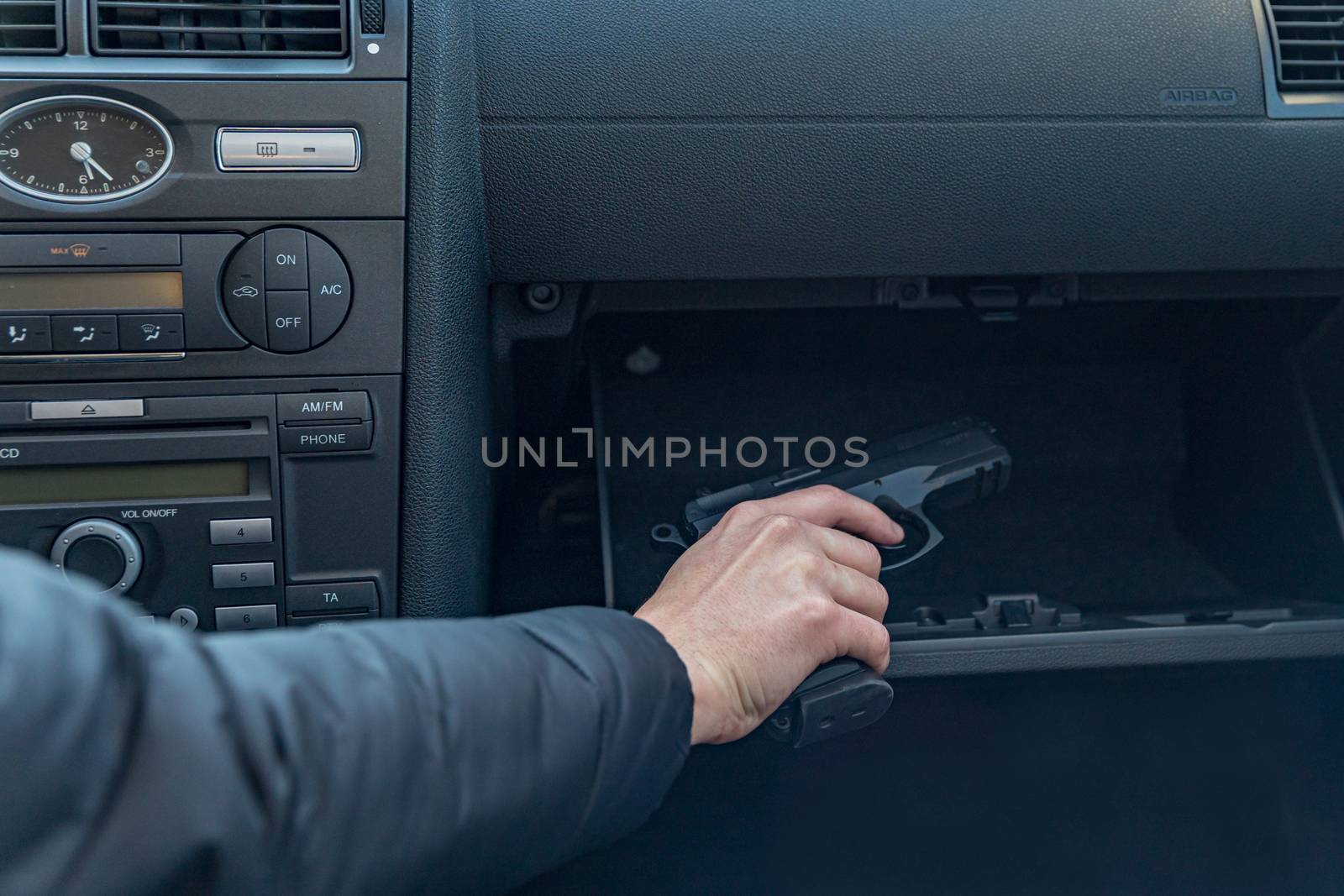 the driver takes the gun from the passenger compartment of the car. Gangster or policeman.