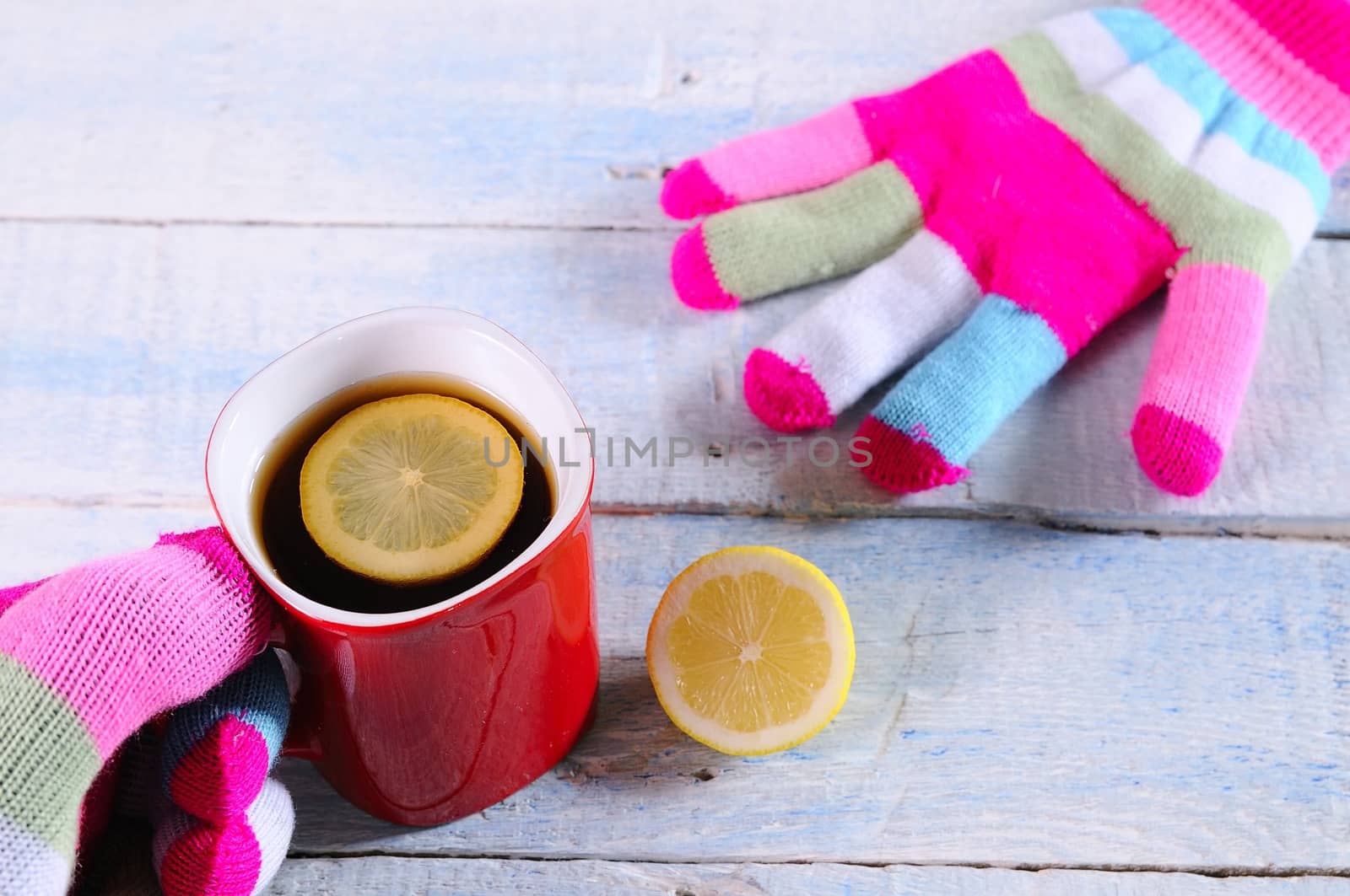 Gloved hands with a cup of hot tea.