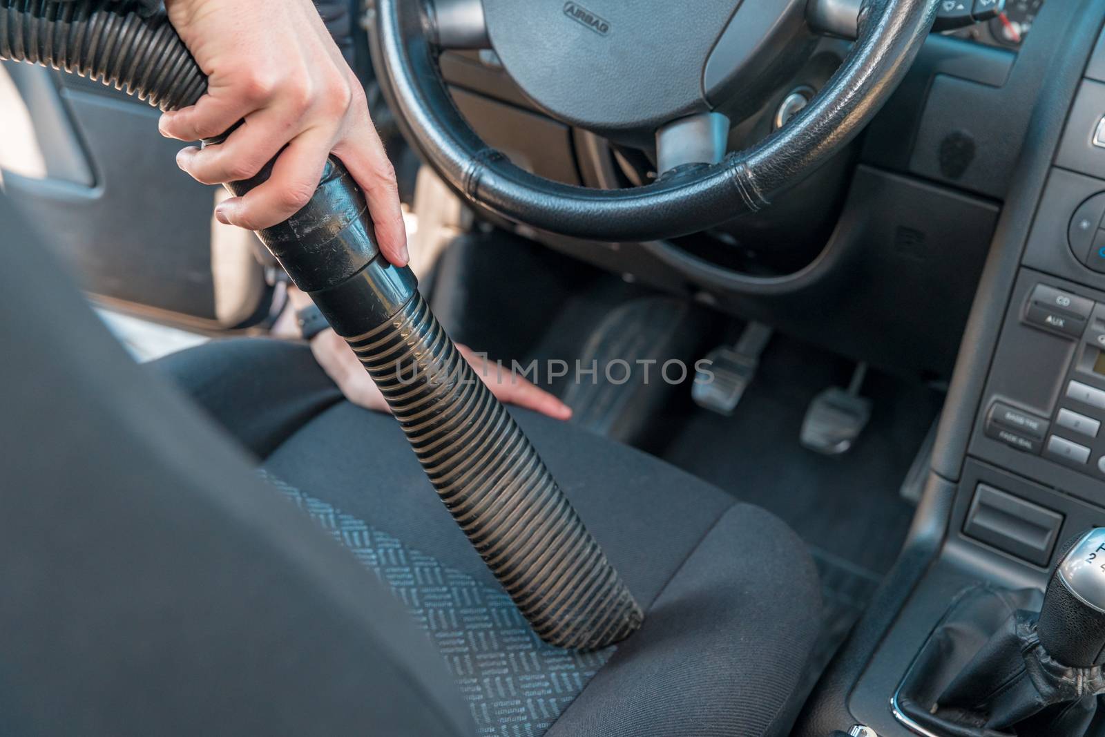 vehicle interior vacuum cleaning. Detail shot of an industrial vacuum cleaner cleaning a car seat.