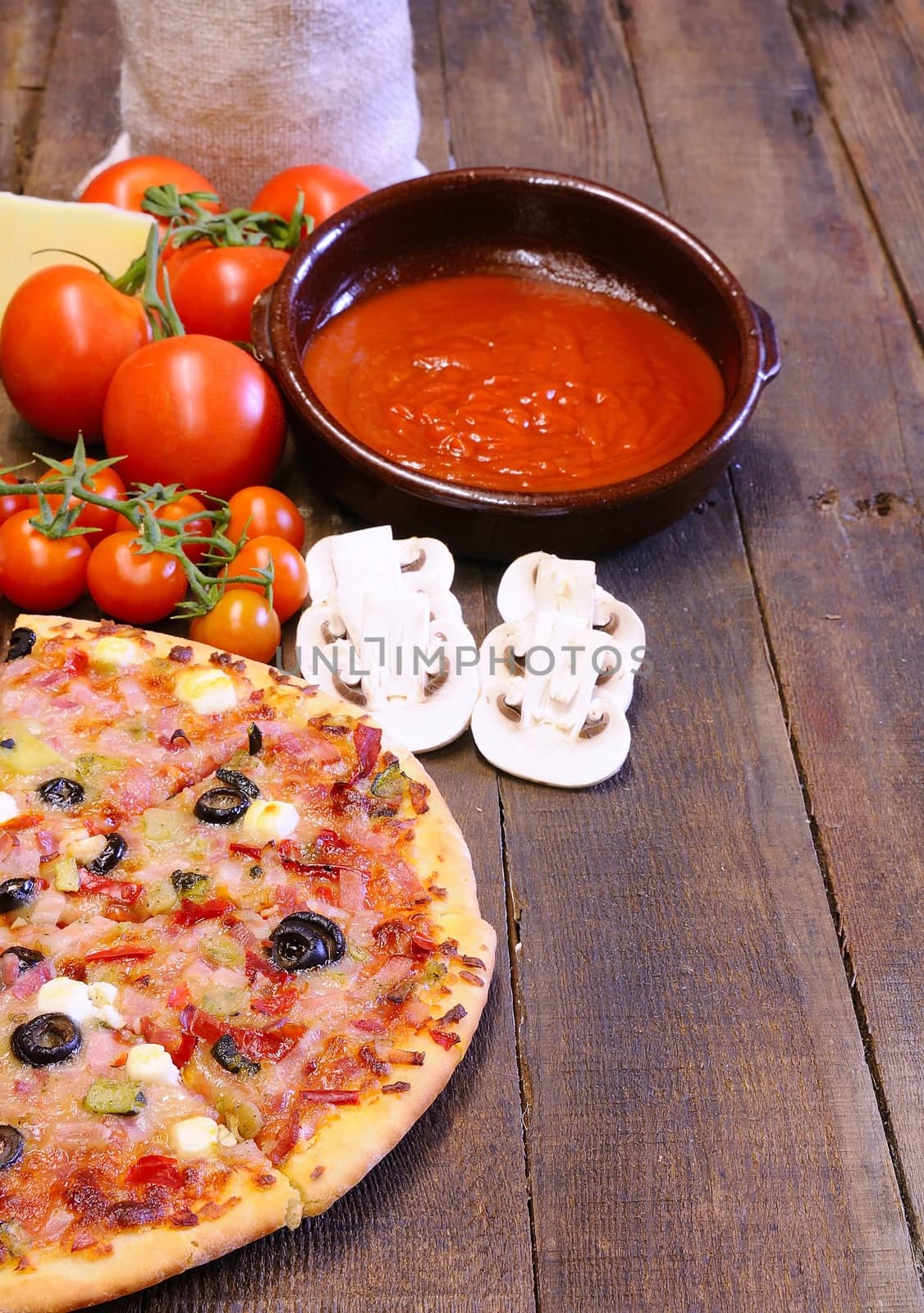 Pizza and ingredients on the kitchen table.