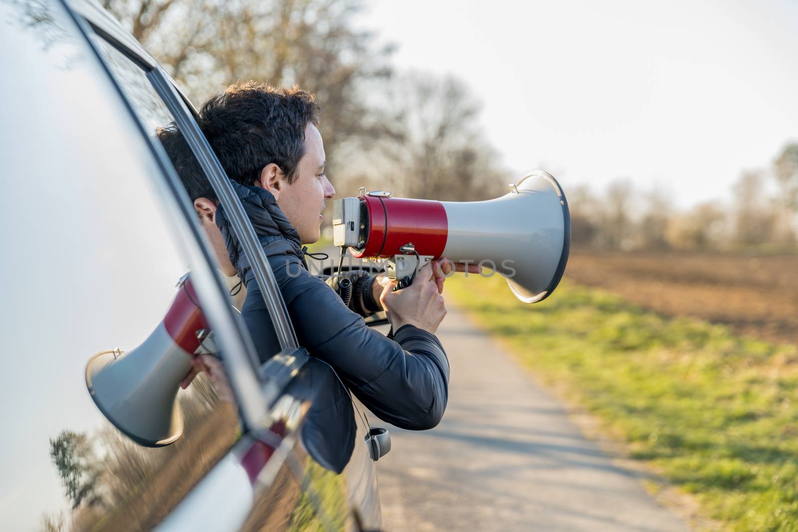 a young man brought into megaphone important news through a car window.