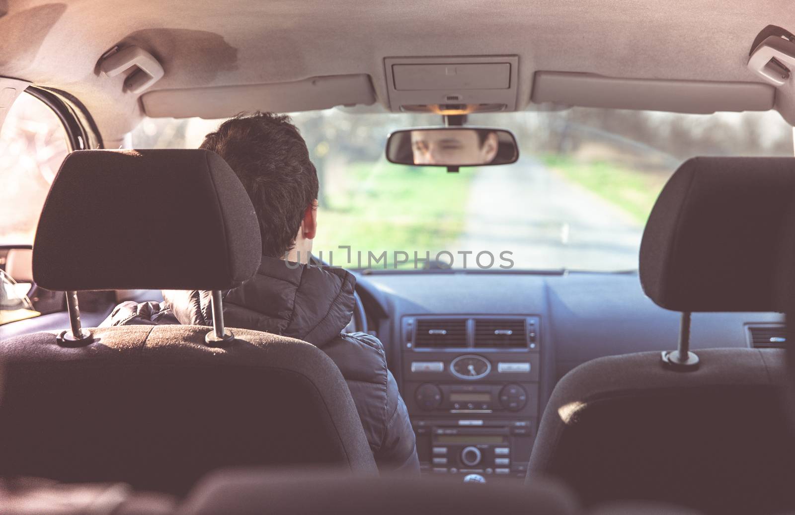 young man in an empty passenger car on the driver's seat. reflection of the eyes in the rearview mirror.