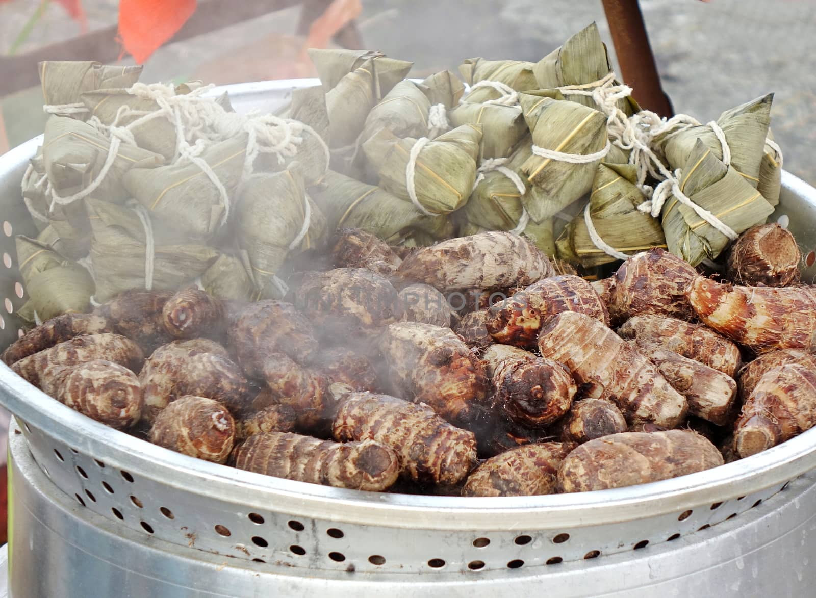 Chinese sticky rice dumplings wrapped in leaves and taro roots in steamer
