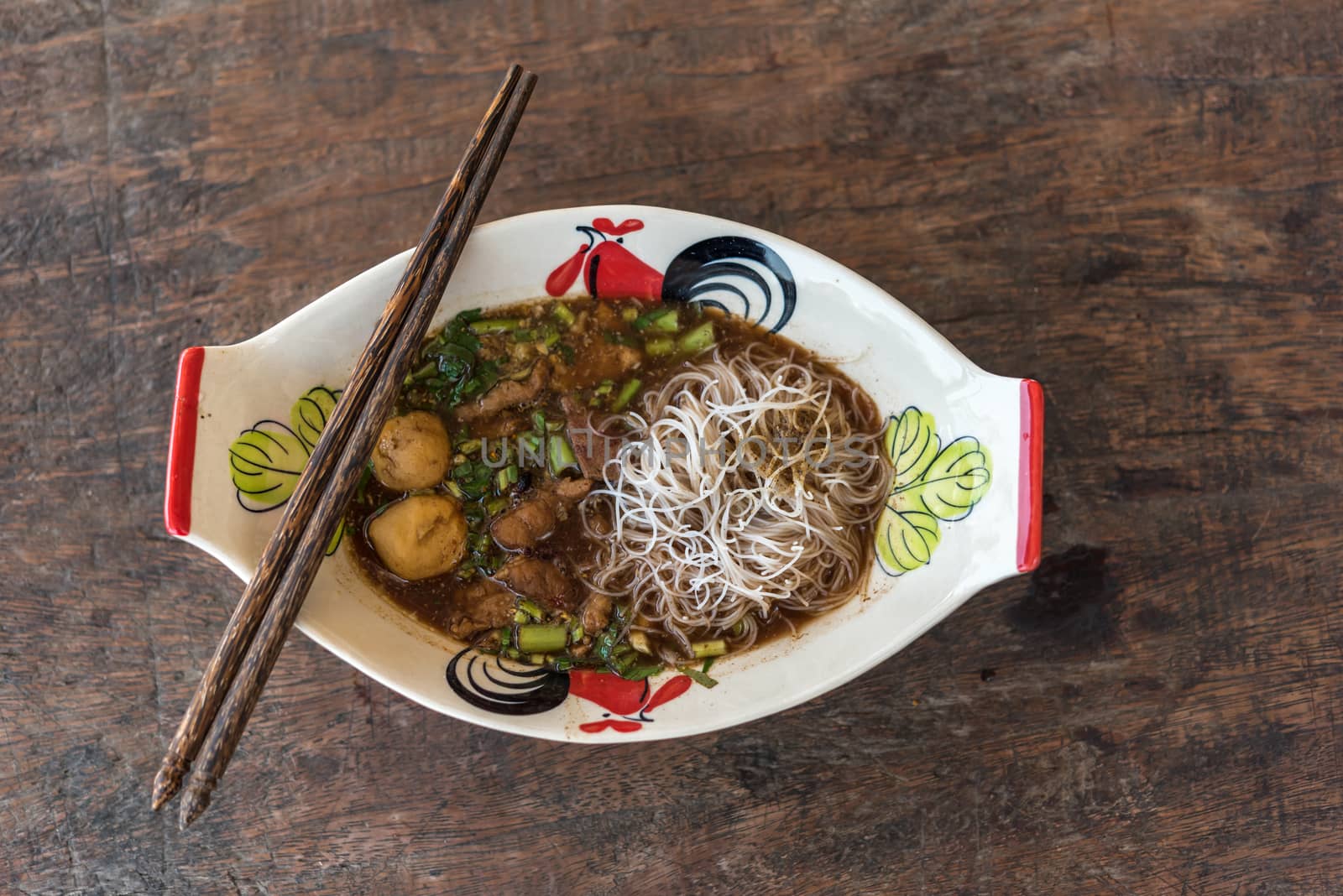 Braised beef clear noodle with meat balls soup stew (Ekaehla meat) with vegetable in bowl for sale at Thai street food market or restaurant in Thailand