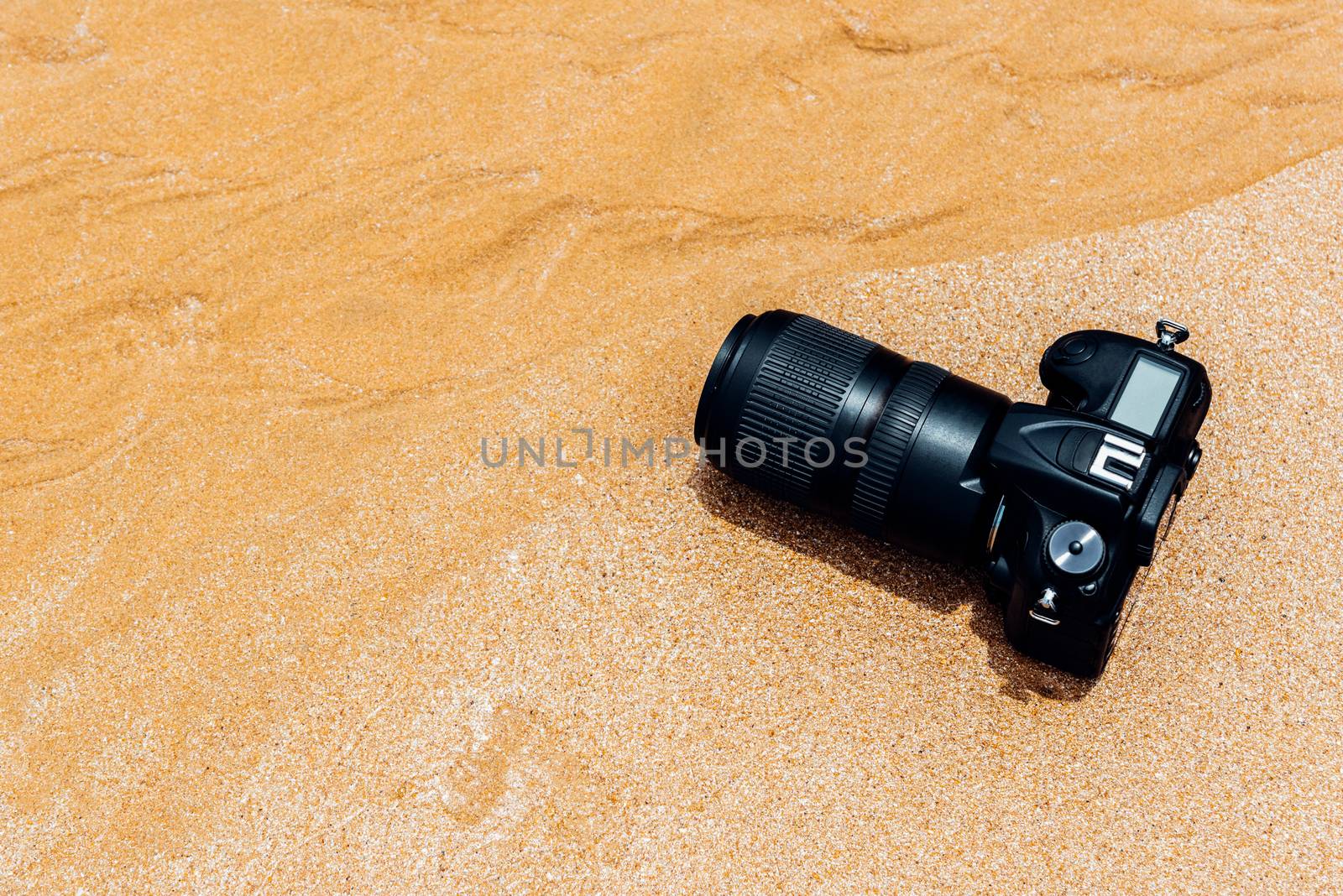 DSLR camera on beach wet from water sea wave by PongMoji