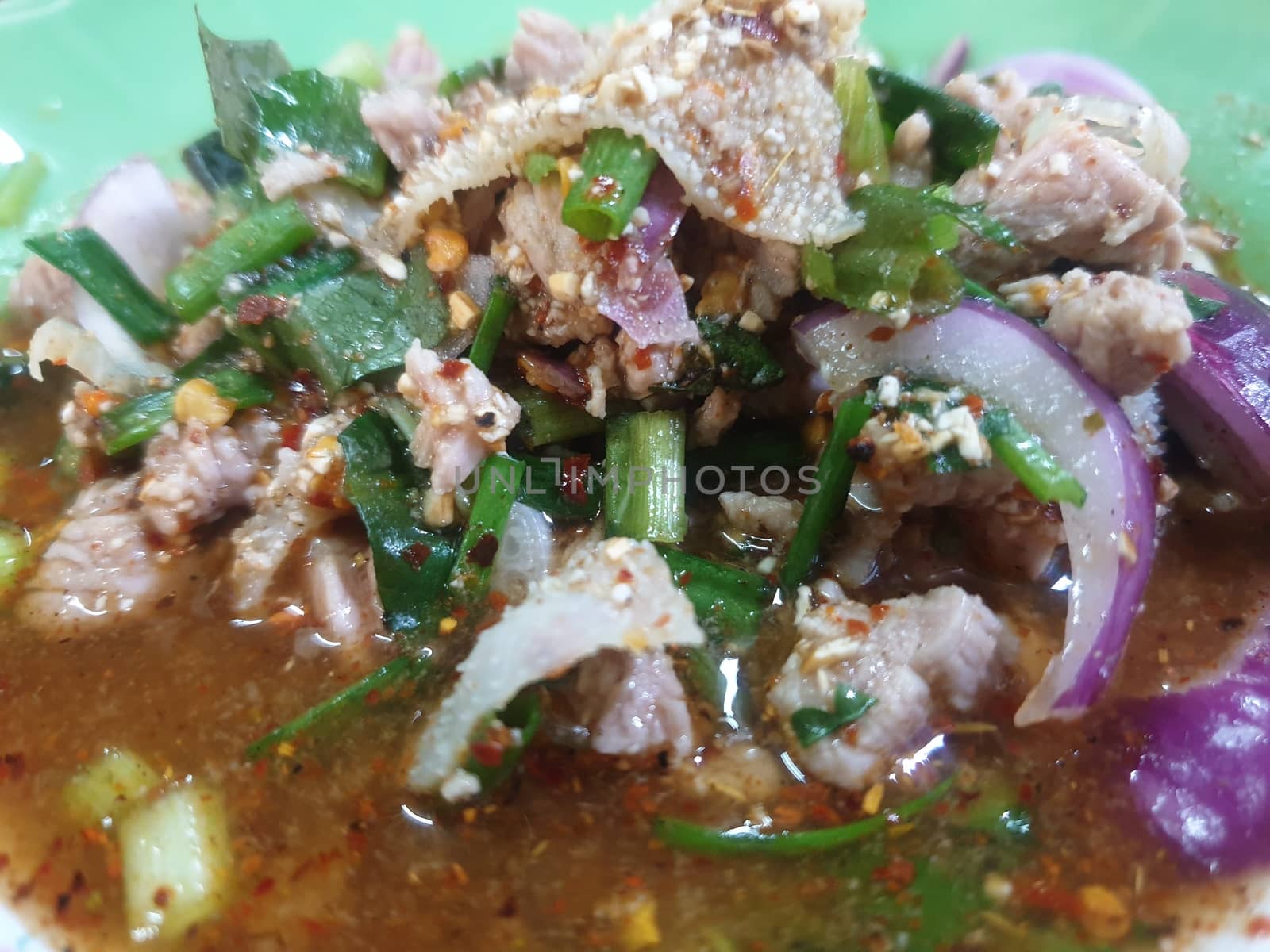 Spicy minced beef salad or Ground beef salad (Laab) is a Thai food for health consists of beef, ground rice, chili, lemon, onion and herb mixed in plate on a wood table at Thai street food