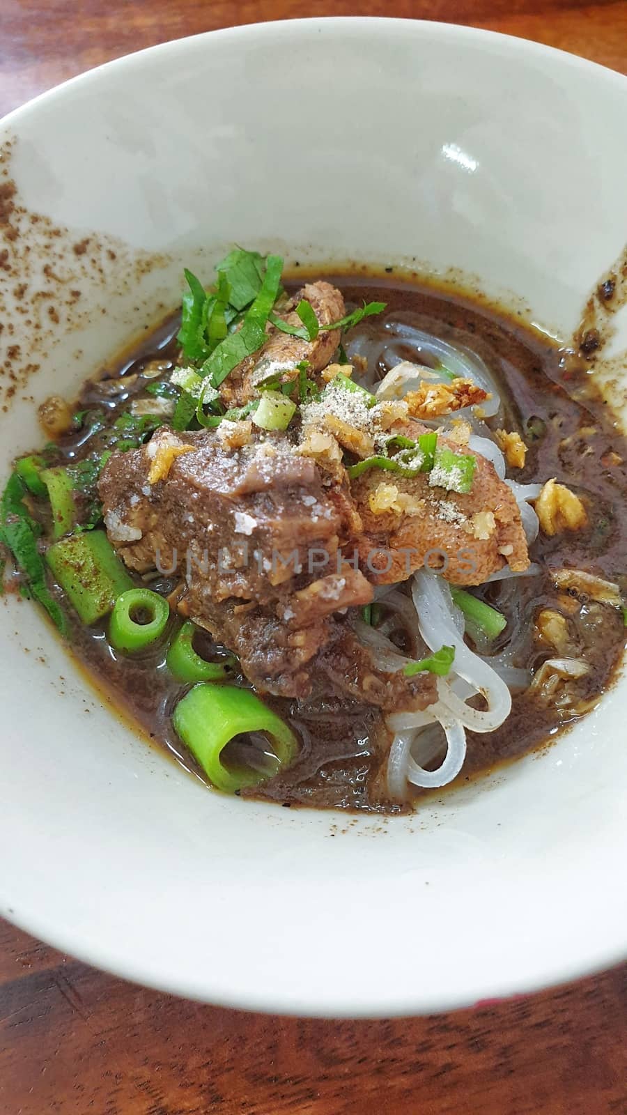 Braised beef clear noodle with meat balls soup stew (Ekaehla meat) with vegetable in bowl for sale at Thai street food market or restaurant in Thailand