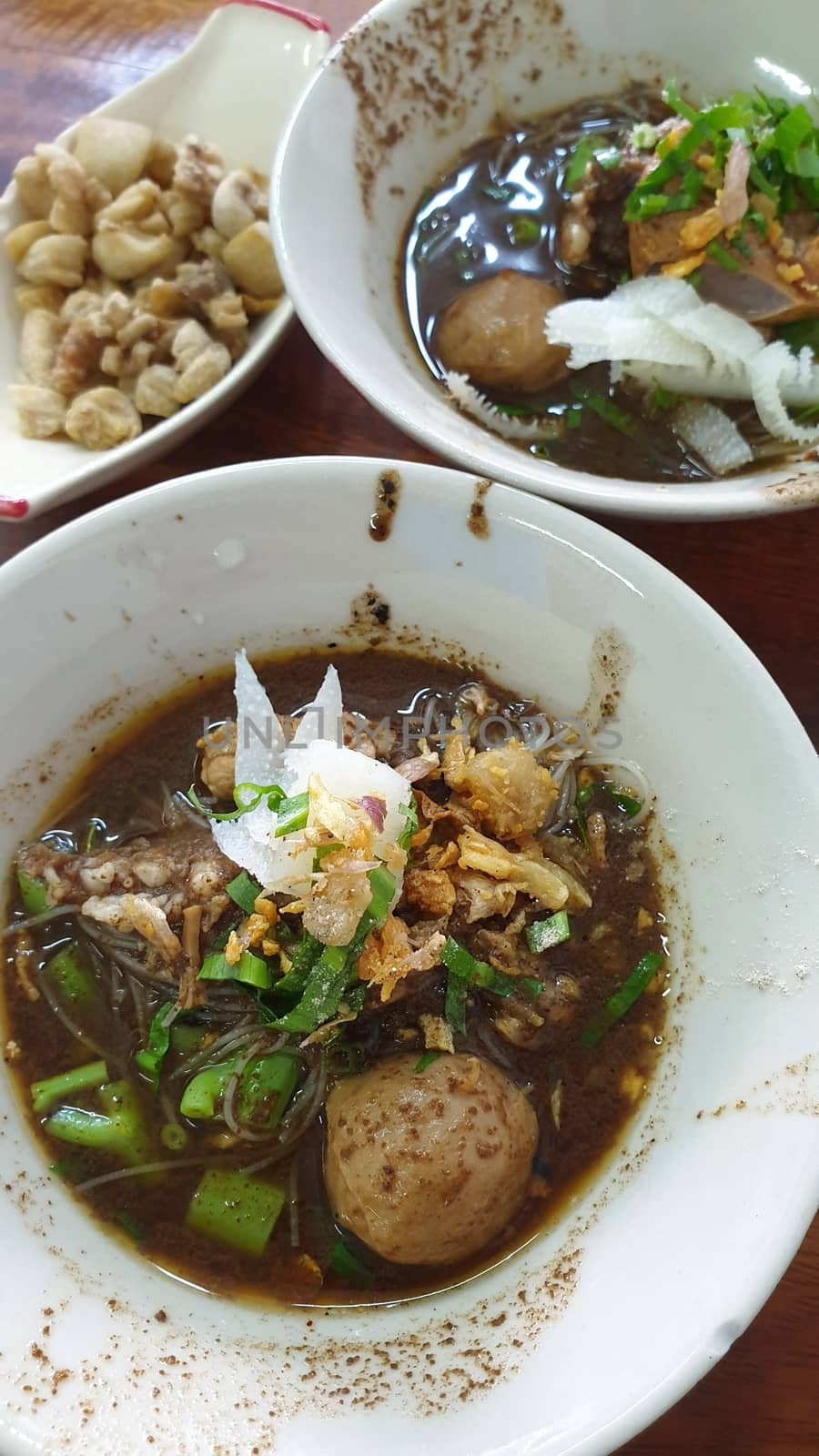 Braised beef clear noodle with meat balls soup stew (Ekaehla meat) with vegetable in bowl for sale at Thai street food market or restaurant in Thailand