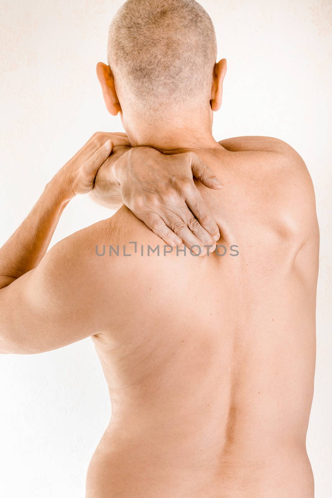 Man massaging his top back, the trapezius muscle, because of a thoracic vertebrae pain due to a displacement of a dorsal vertebra rubbing on a nerve