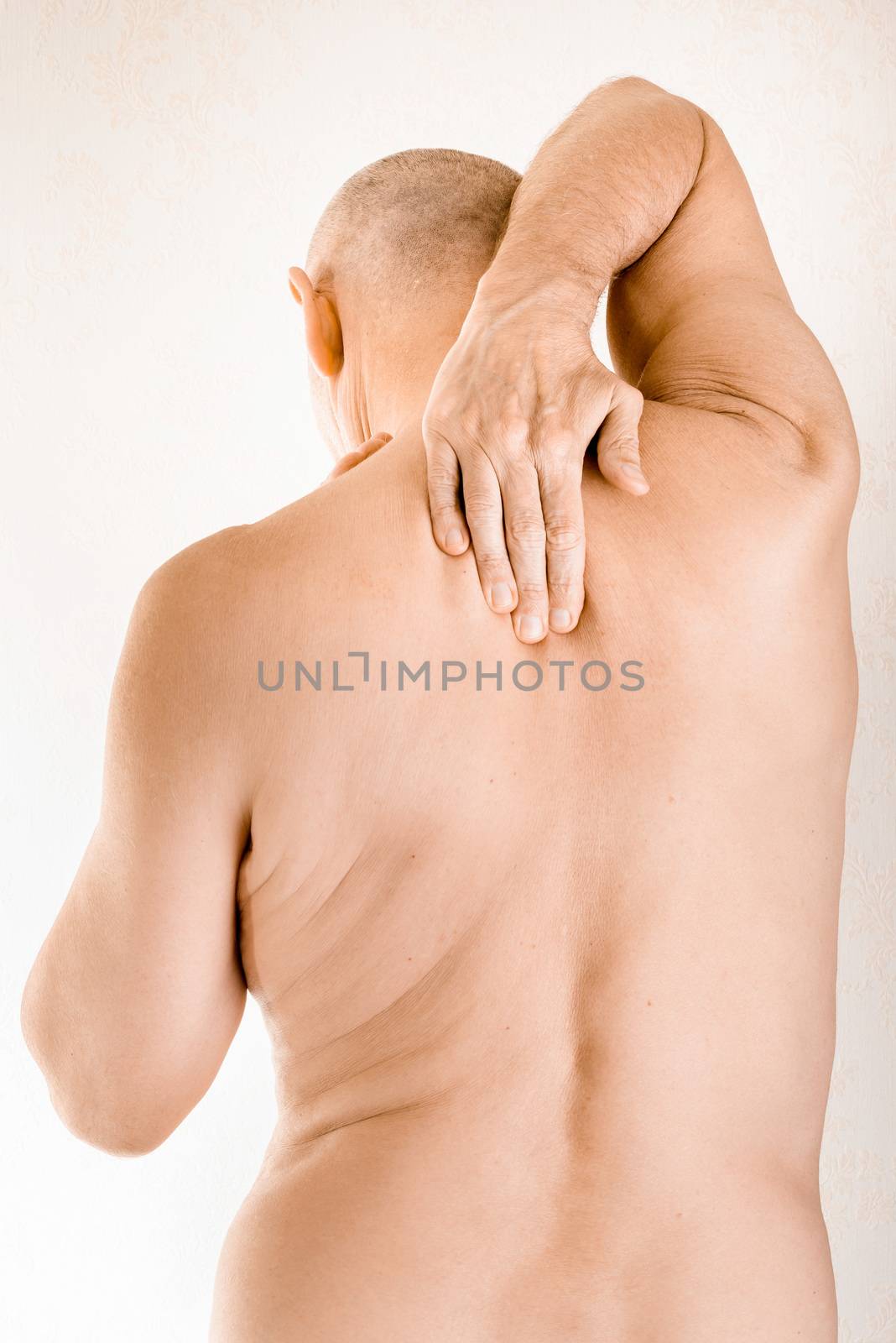 Man massaging his top back, between the shoulders, because of a thoracic vertebrae pain due to a displacement of a dorsal vertebra rubbing on a nerve