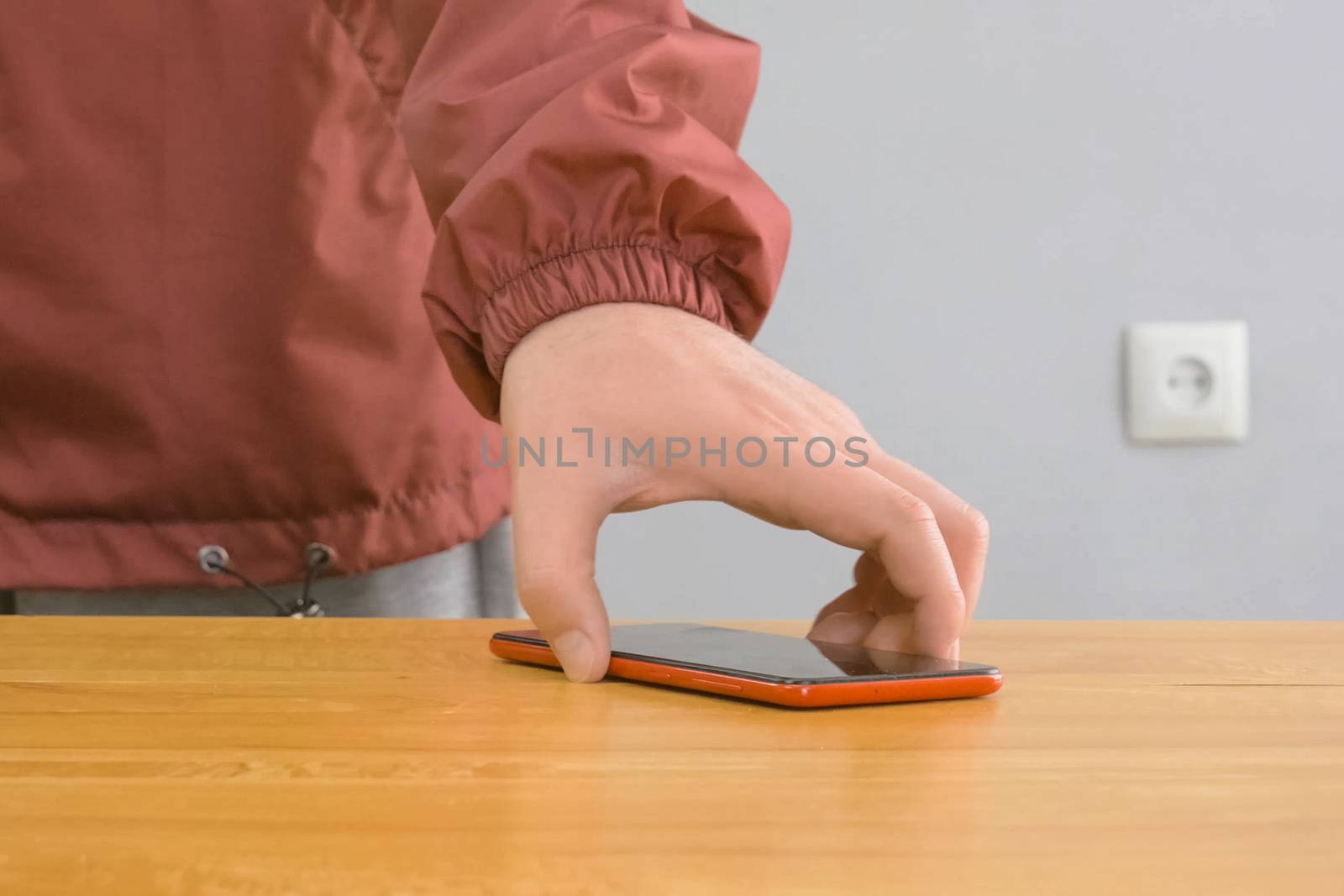 A man lifts his phone from the table with his hand.