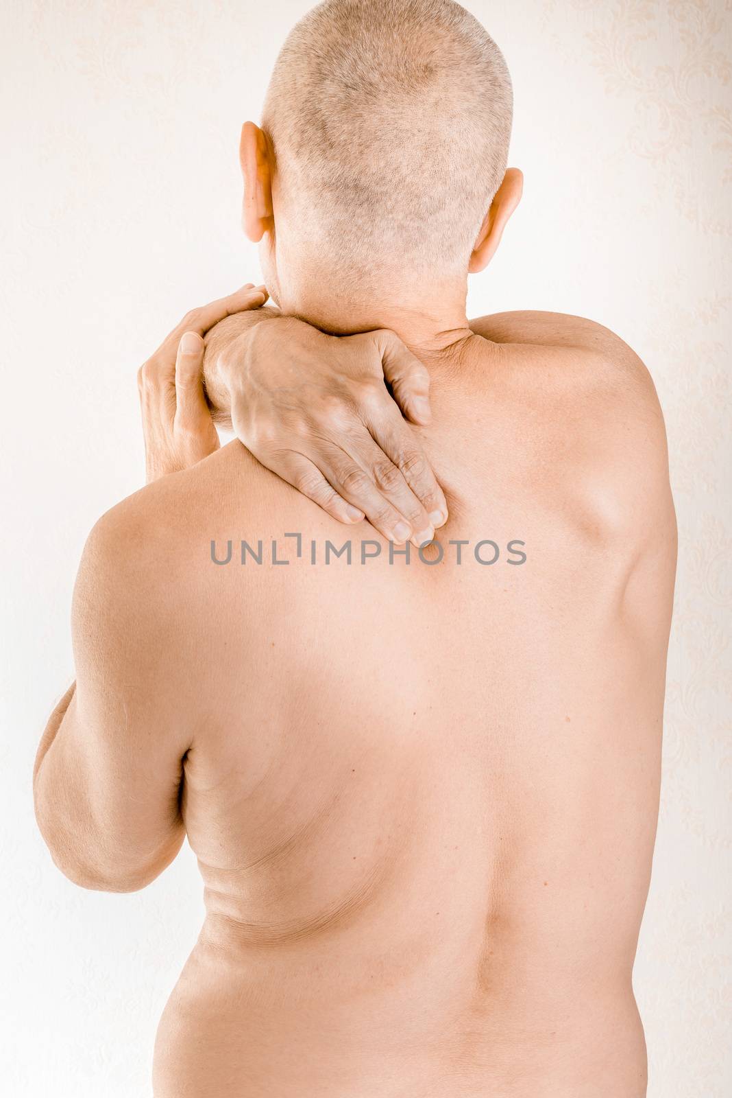 Man massaging his top back, the trapezius muscle, because of a thoracic vertebrae pain due to a displacement of a dorsal vertebra rubbing on a nerve