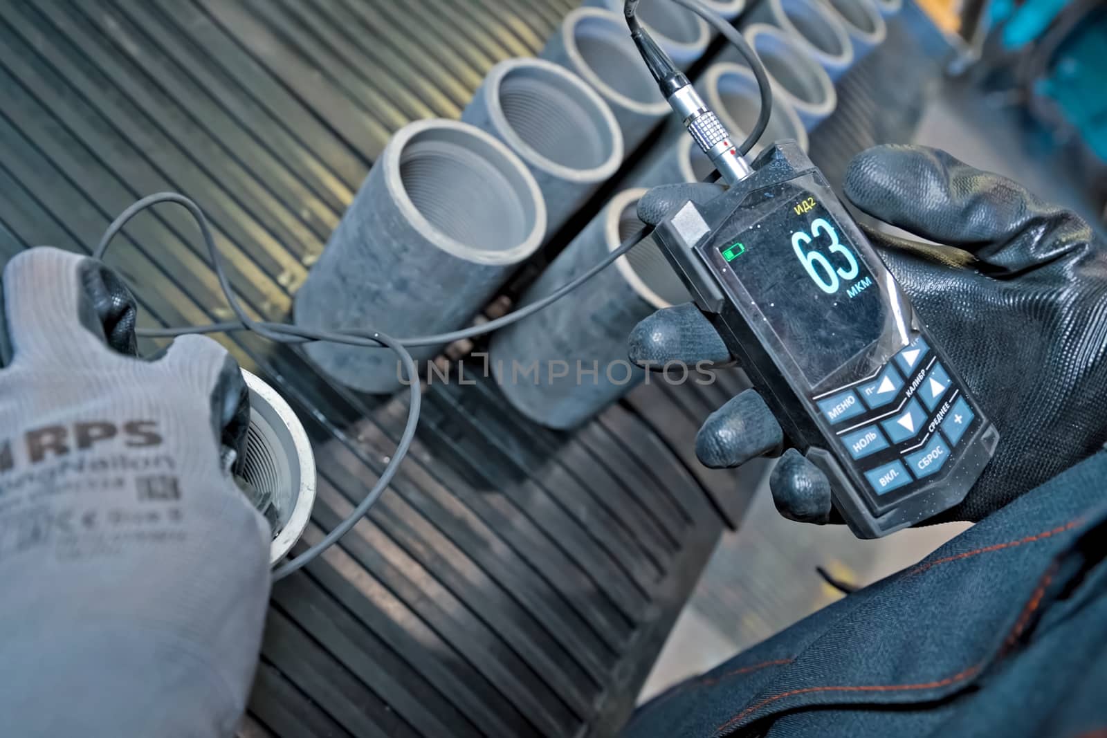 worker measures the thickness of the couplings of pumping oil pipes. by DePo