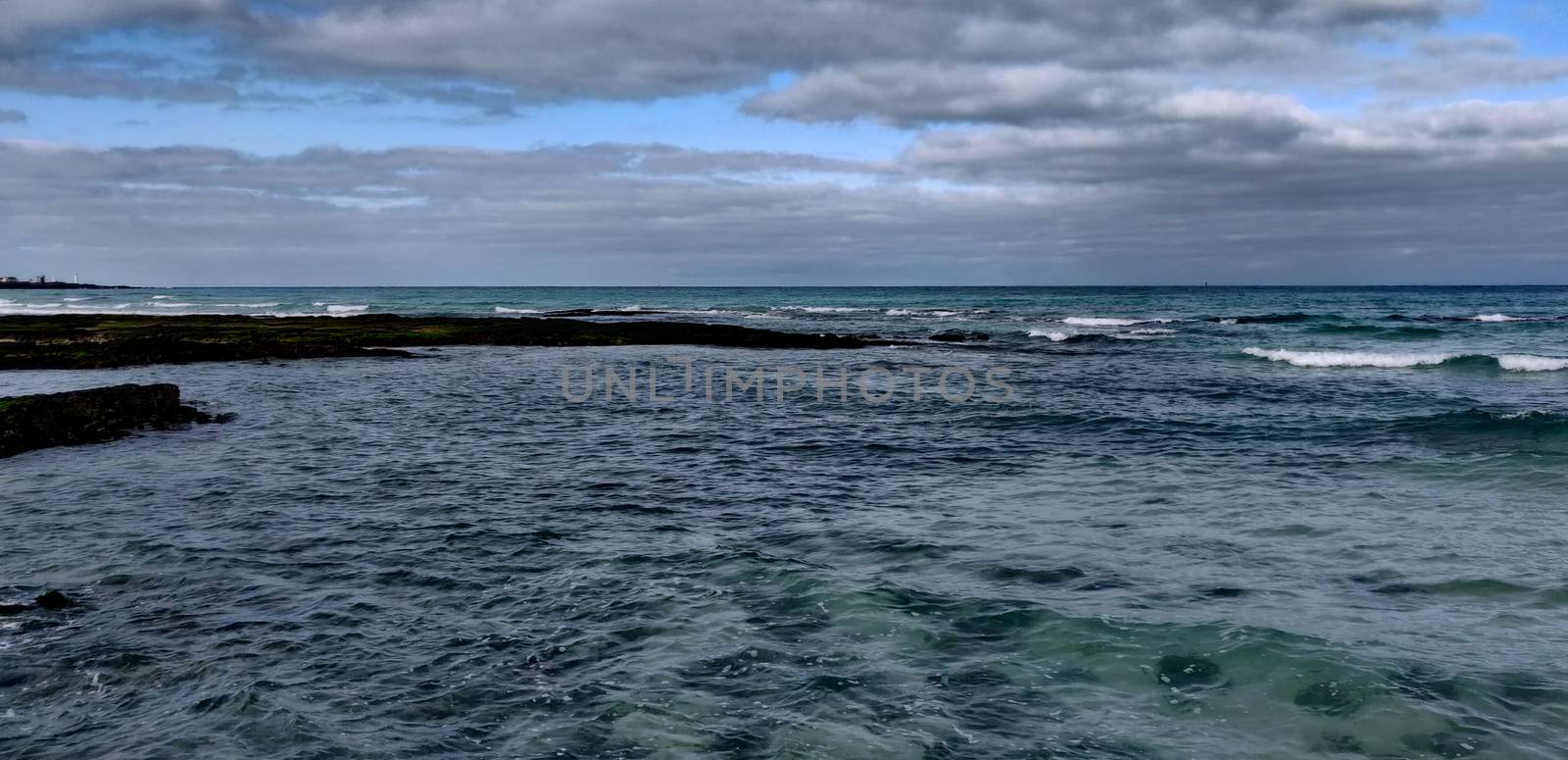 Cobalt blue sea hitting ancient volcanic rocks on Hyeopjae beach in Jeju Island, South Korea