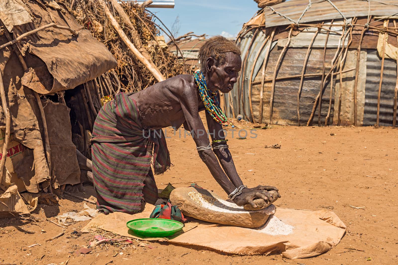 OMO VALLEY, ETHIOPIA - MAY 6, 2015 : Old woman from the African tribe Dasanesh working hard in front of her hut.