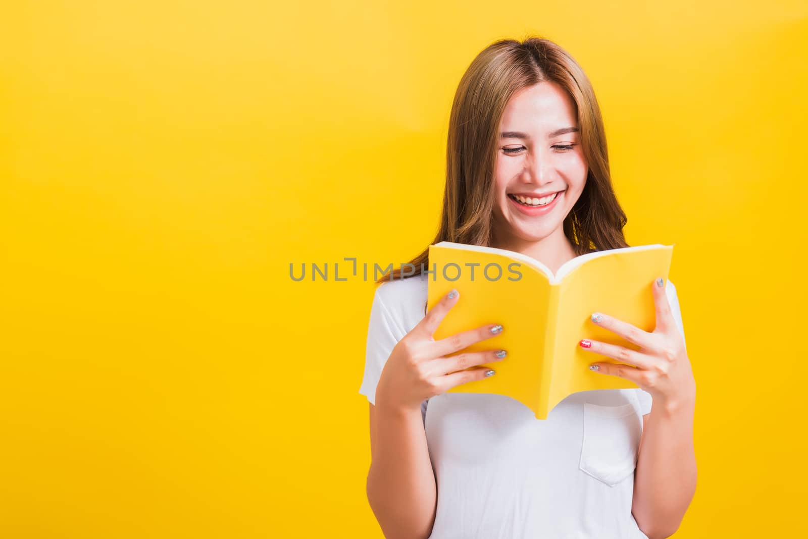Portrait Asian Thai beautiful happy young lifestyle woman stands holding yellow book or diary her looking to book, studio shot isolated on yellow background, with copy space