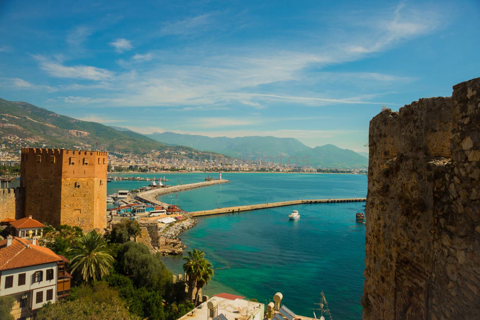 Kizil Kule tower. Top view of the lighthouse at the port in Alanya, Antalya district, Turkey, Asia. Famous tourist destination with high mountains. Part of ancient old Castle. Summer bright day