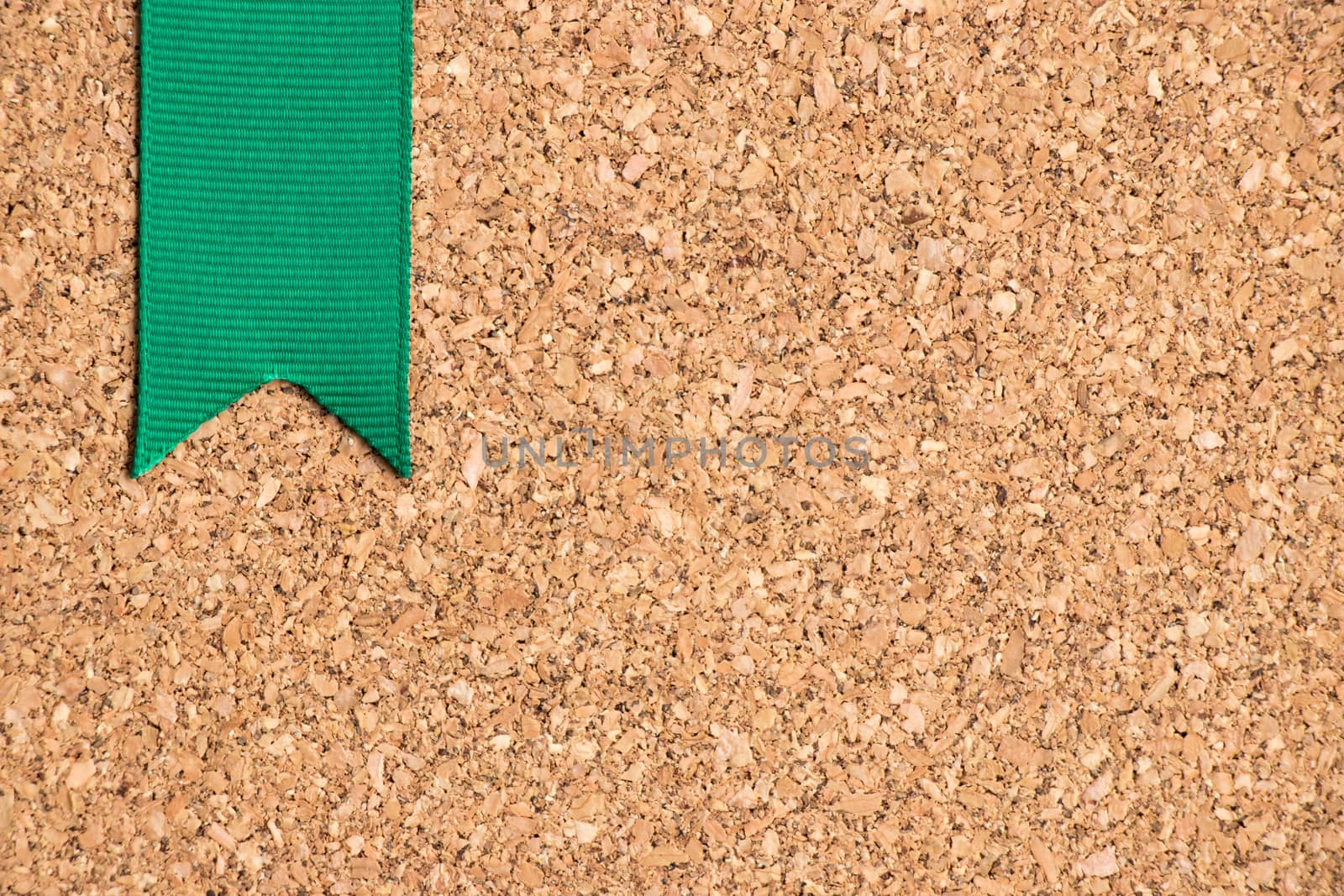 Green ribbon on cork board texture background