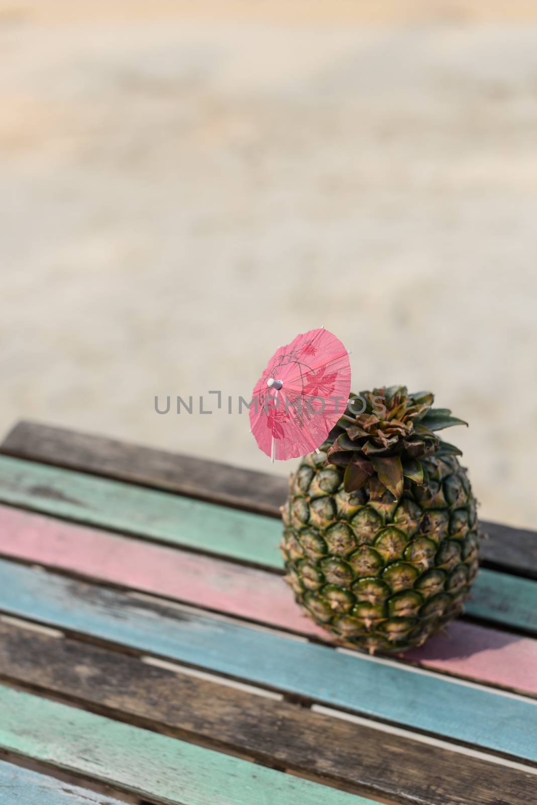 Pineapple fruit on vintage wood table with beach sand background