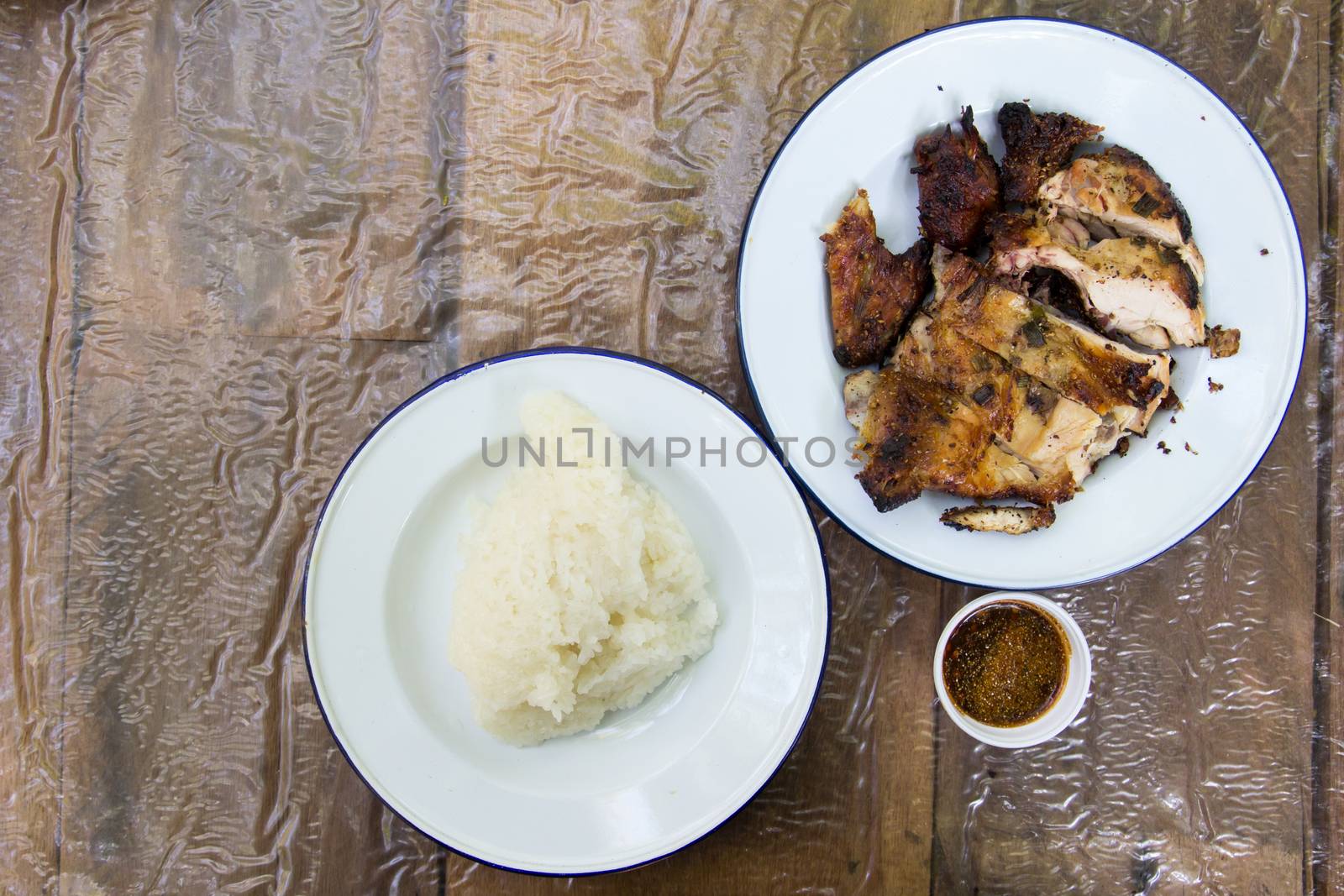 Grilled chicken and sticky rice on wooden background