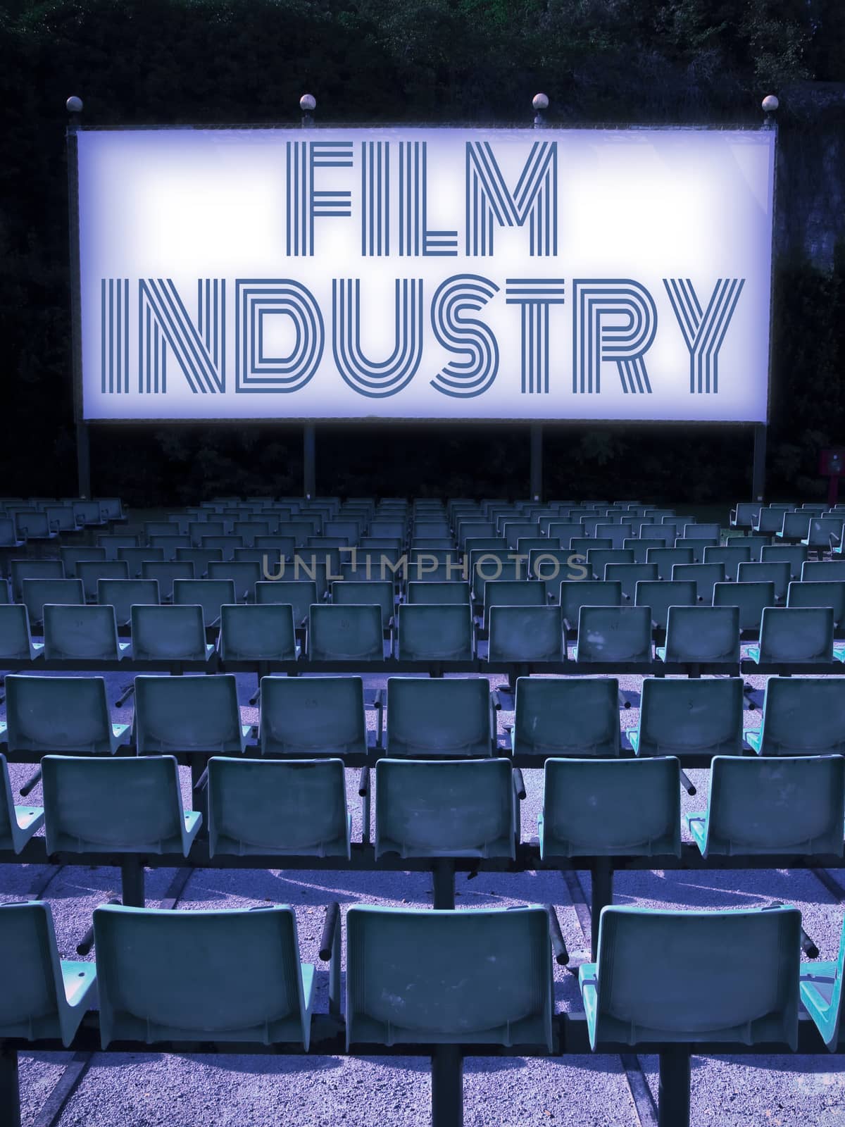Outdoor cinema with plastic chairs in a row and Film Industry on screen - concept image.