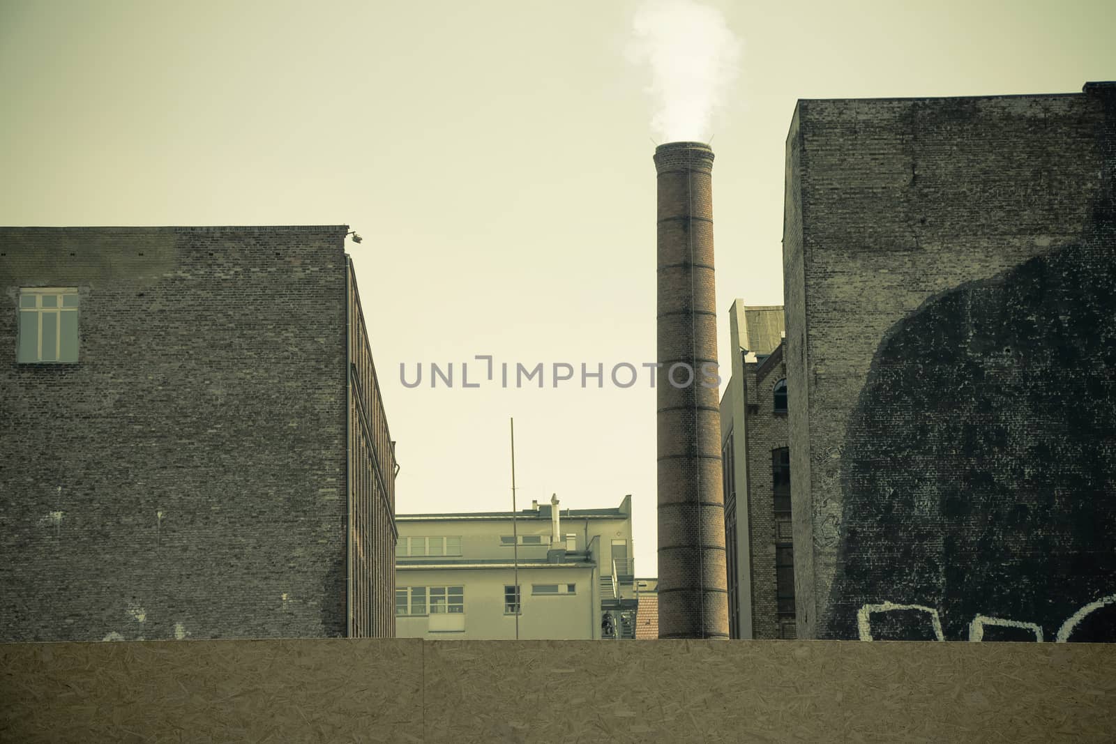 Smoke emitted from an industrial brick chimney in an old factory building. It located in Berlin, Germany.