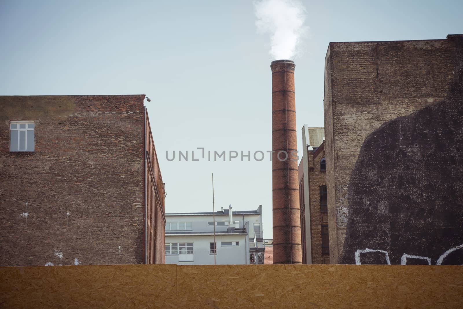 Smoke emitted from an industrial brick chimney in an old factory building. It located in Berlin, Germany.
