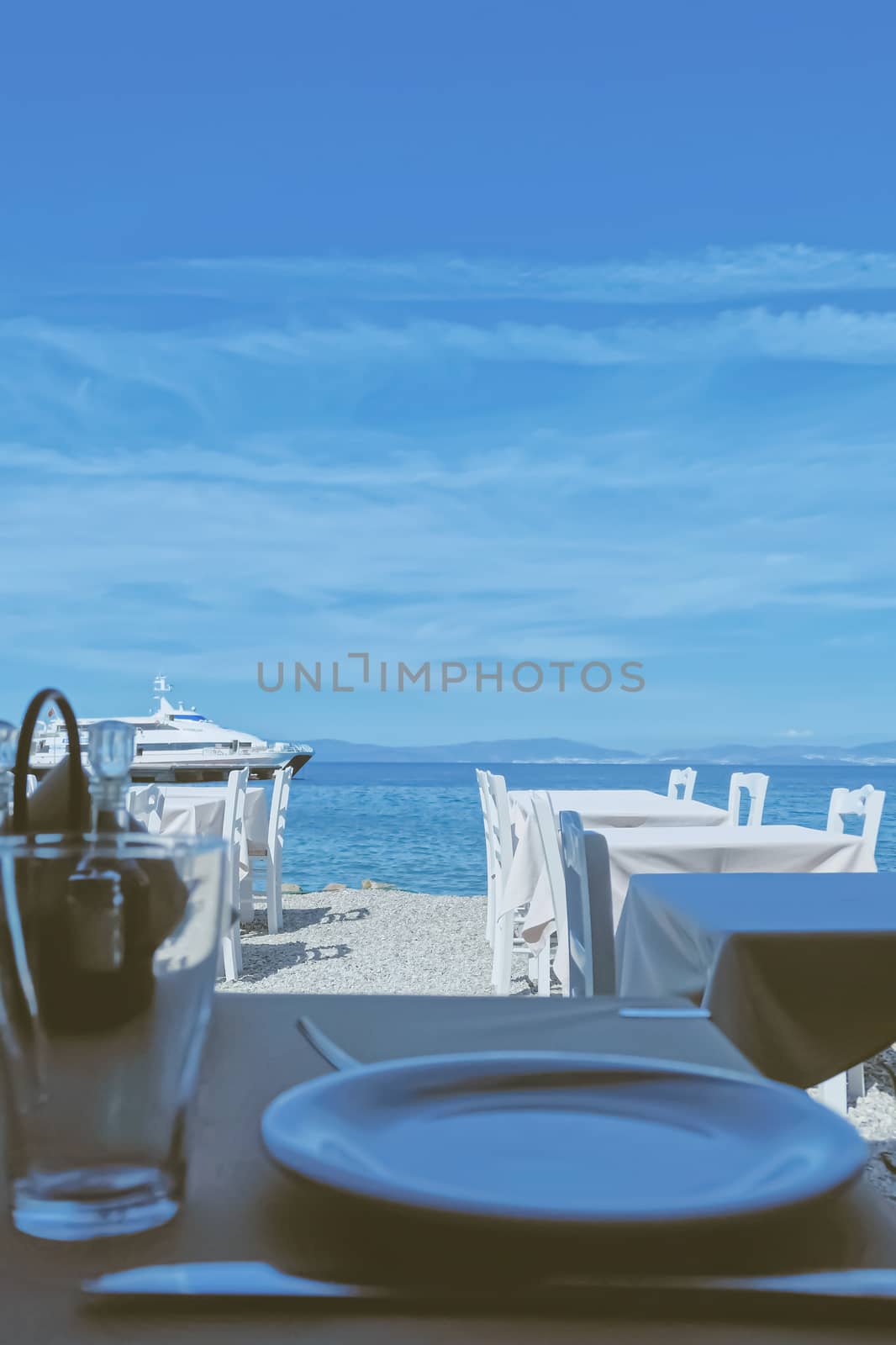 Empty restaurant by the Aegean sea and cruise boat, travel and nature by Anneleven