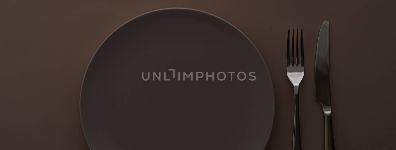 Empty plate and cutlery as mockup set on dark brown background, top tableware for chef table decor and menu branding design