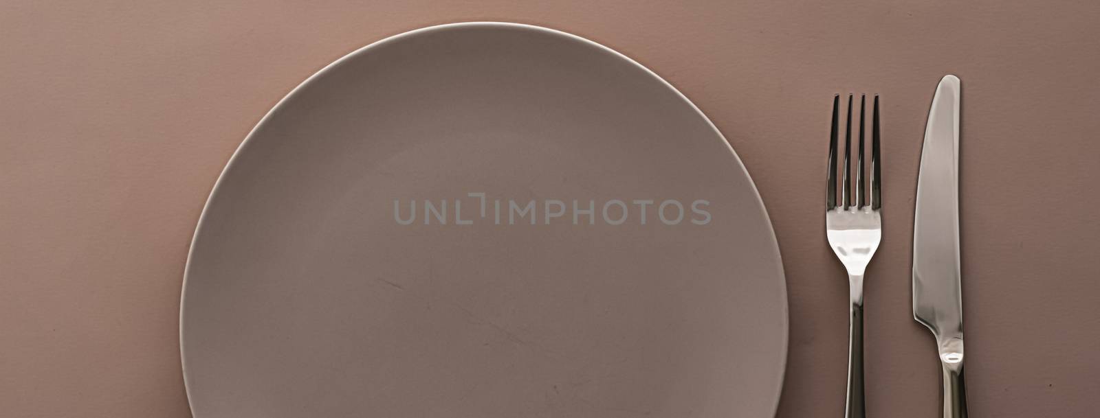 Empty plate and cutlery as mockup set on brown background, top tableware for chef table decor and menu branding by Anneleven