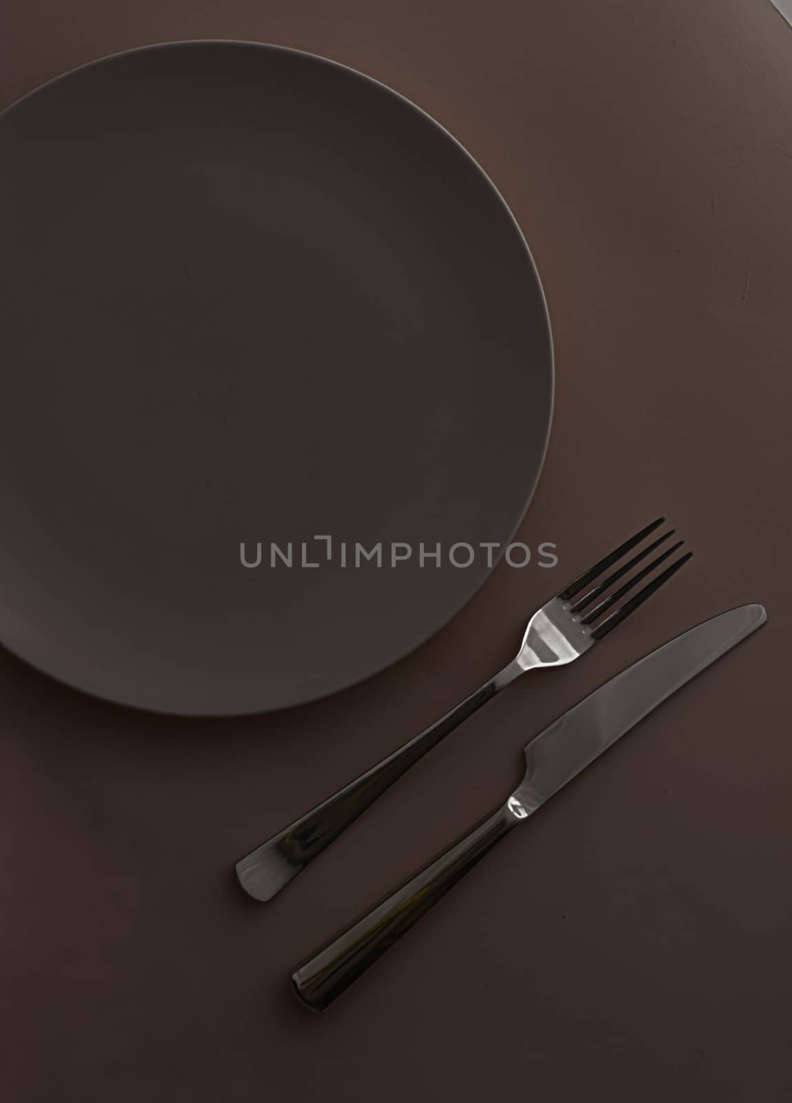 Empty plate and cutlery as mockup set on dark brown background, top tableware for chef table decor and menu branding design