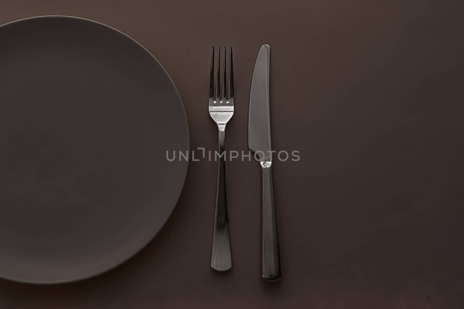 Empty plate and cutlery as mockup set on dark brown background, top tableware for chef table decor and menu branding design