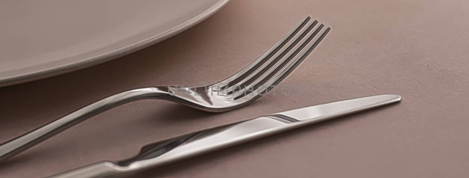 Empty plate and cutlery as mockup set on brown background, top tableware for chef table decor and menu branding by Anneleven