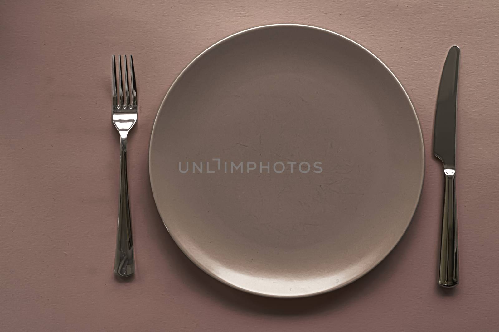 Empty plate and cutlery as mockup set on brown background, top tableware for chef table decor and menu branding by Anneleven