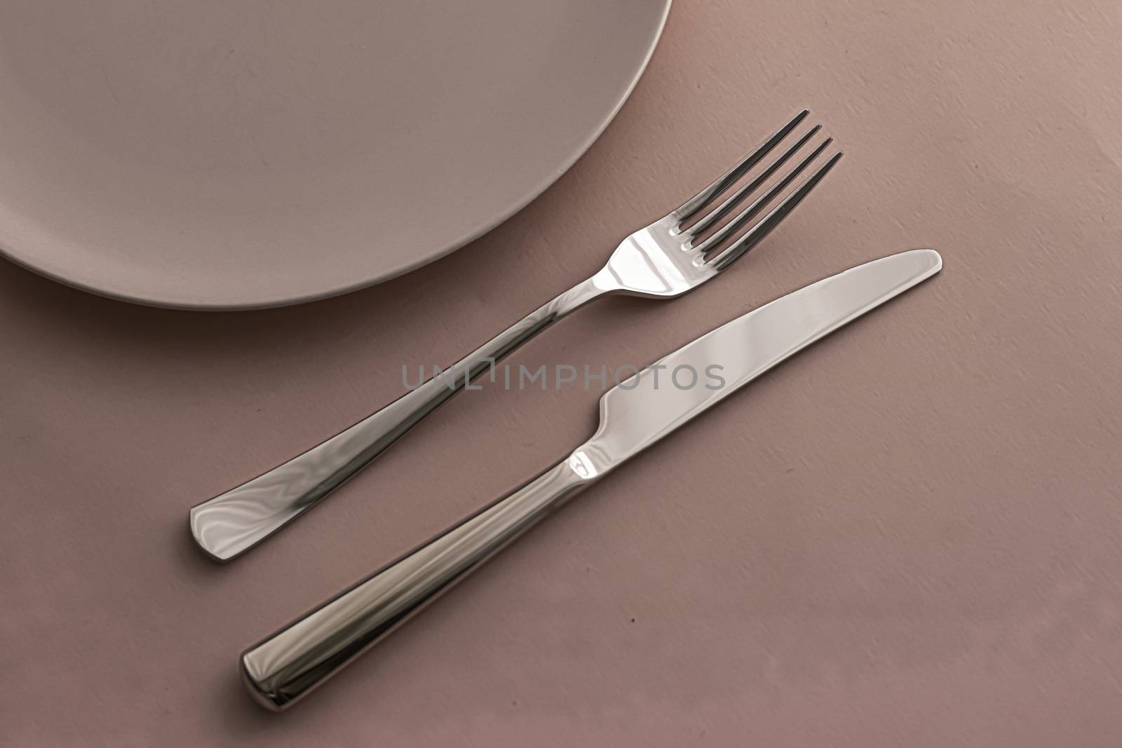 Empty plate and cutlery as mockup set on brown background, top tableware for chef table decor and menu branding by Anneleven